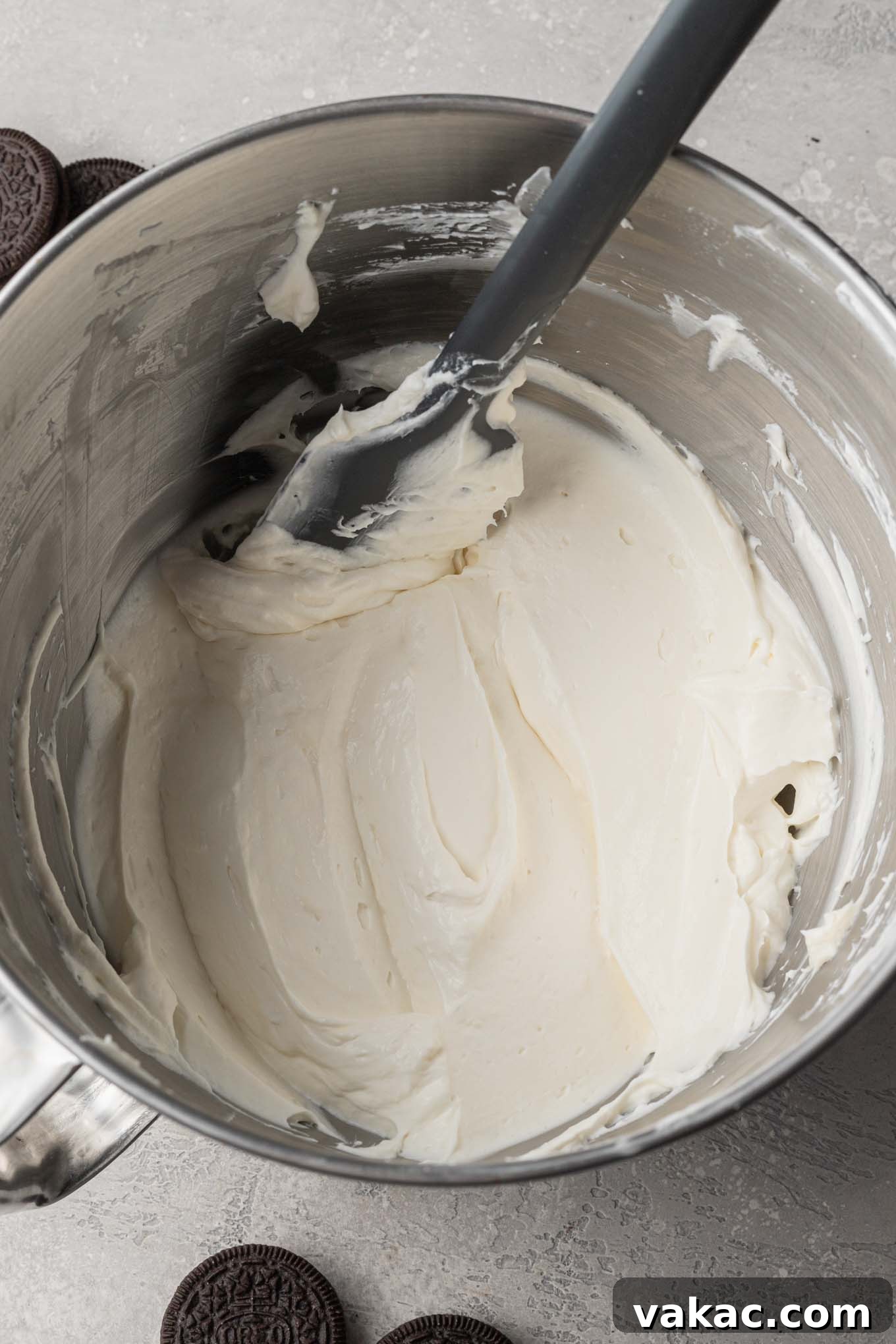 Irresistible Oreo Dream Pie 7 An overhead view of fluffy whipped cream being gently folded into the smooth cream cheese mixture using a spatula.