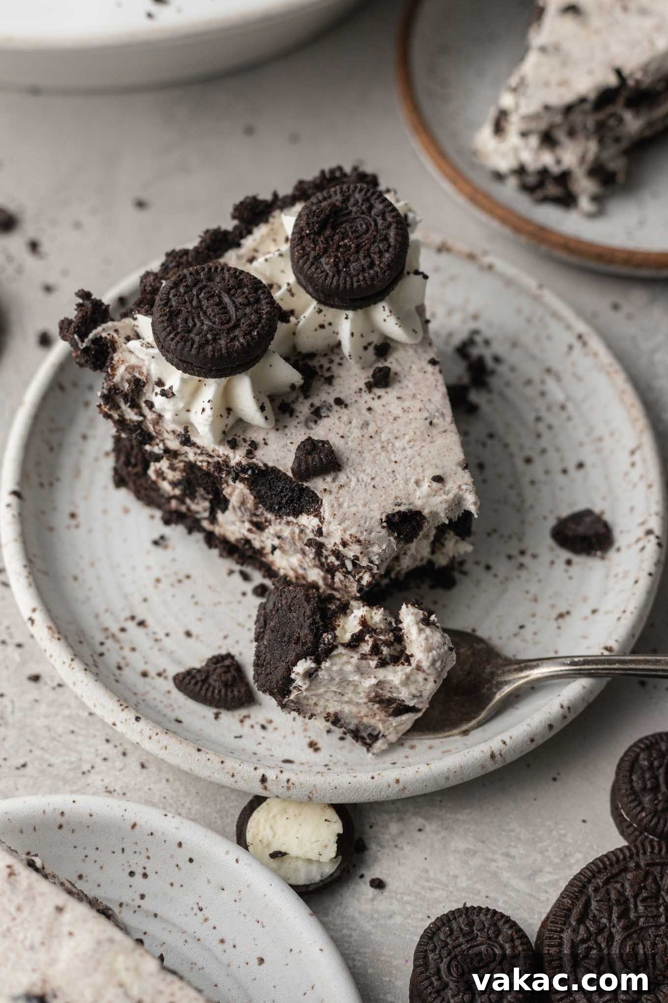 Irresistible Oreo Dream Pie 10 A slice of Oreo pie on a speckled white dessert plate, with a fork resting on the plate having removed a piece of the pie.
