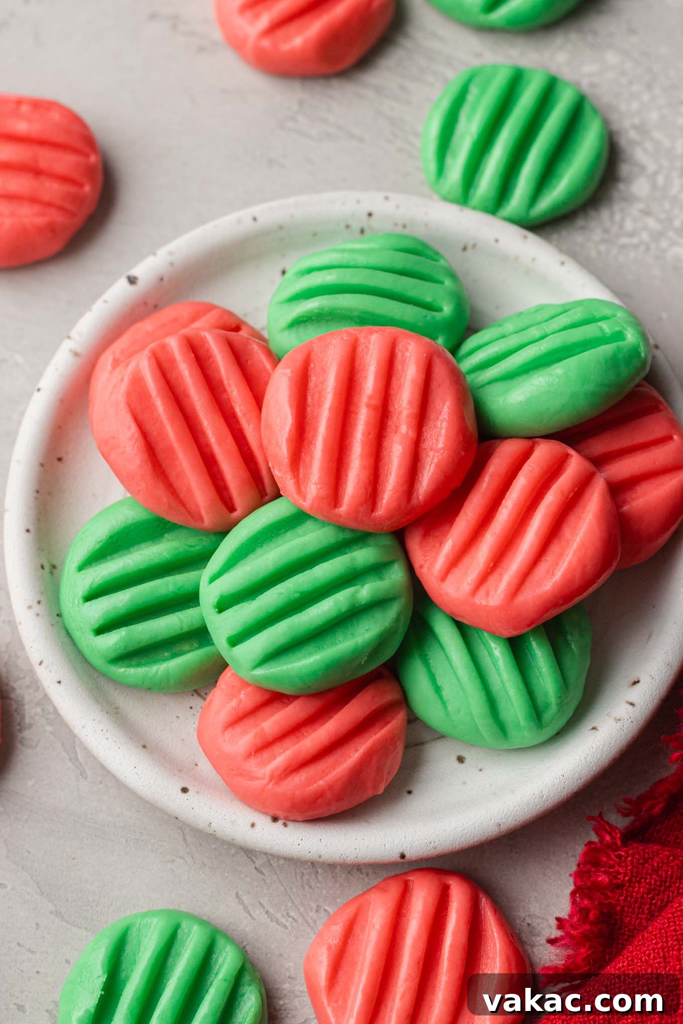 An overhead view of a plate piled high with perfectly shaped homemade cream cheese mints, showcasing their delicate texture and inviting appearance.