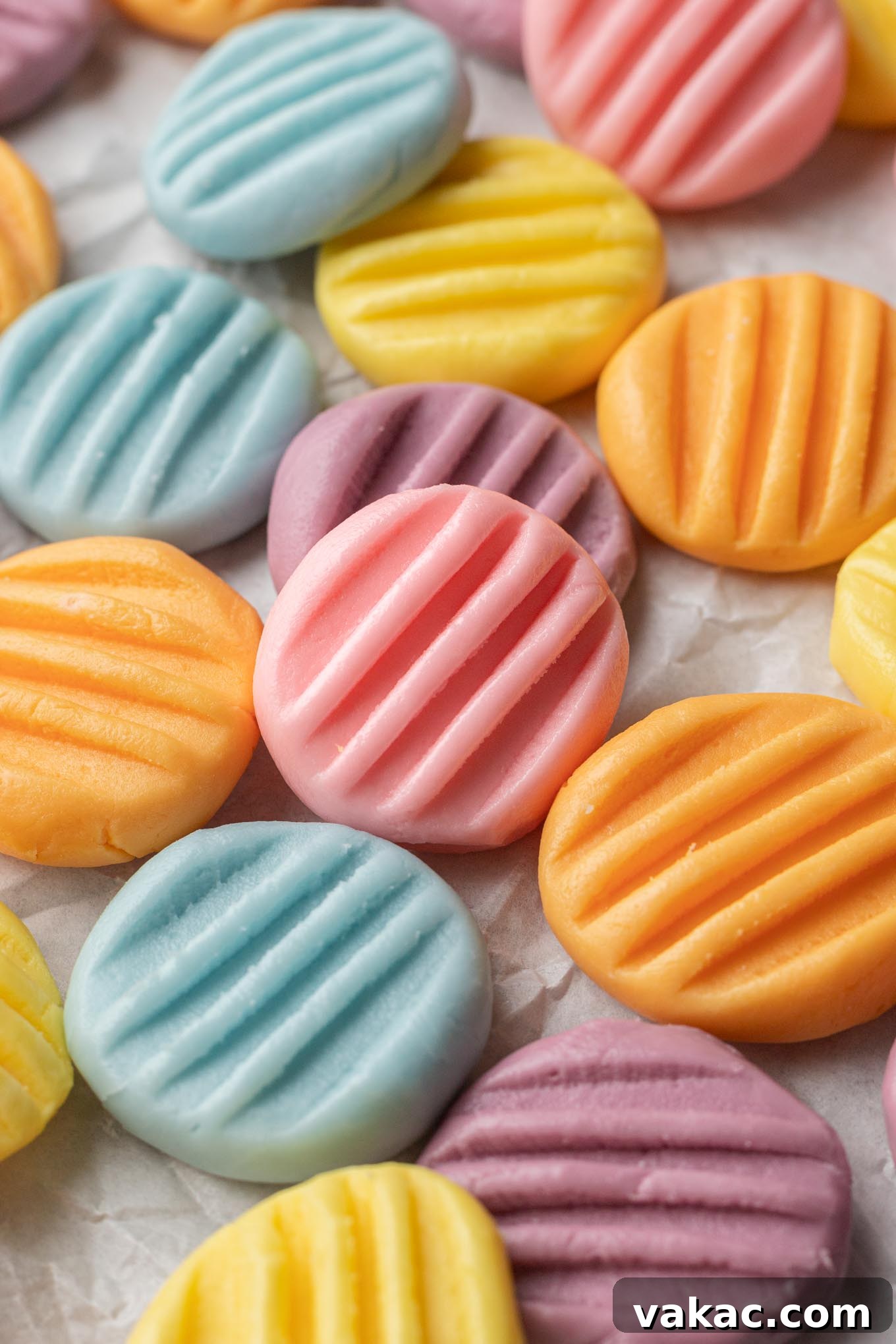 An artistic arrangement of pastel-colored cream cheese mints, delicately placed on parchment paper, inviting contemplation of their diverse flavors and festive appeal.