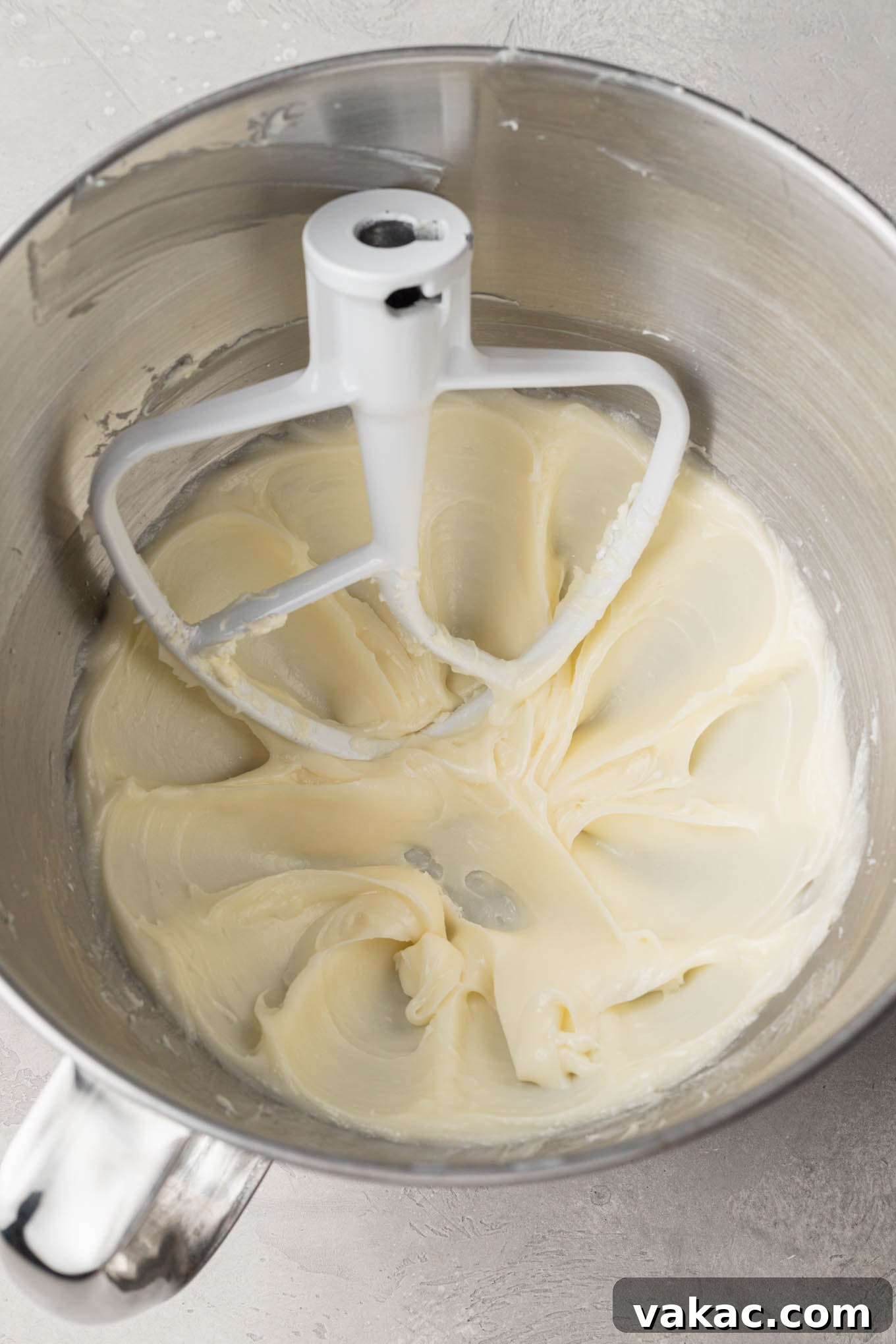 An overhead view of the cream cheese mint mixture after initial mixing, showing a smooth, thick consistency ready for more powdered sugar.