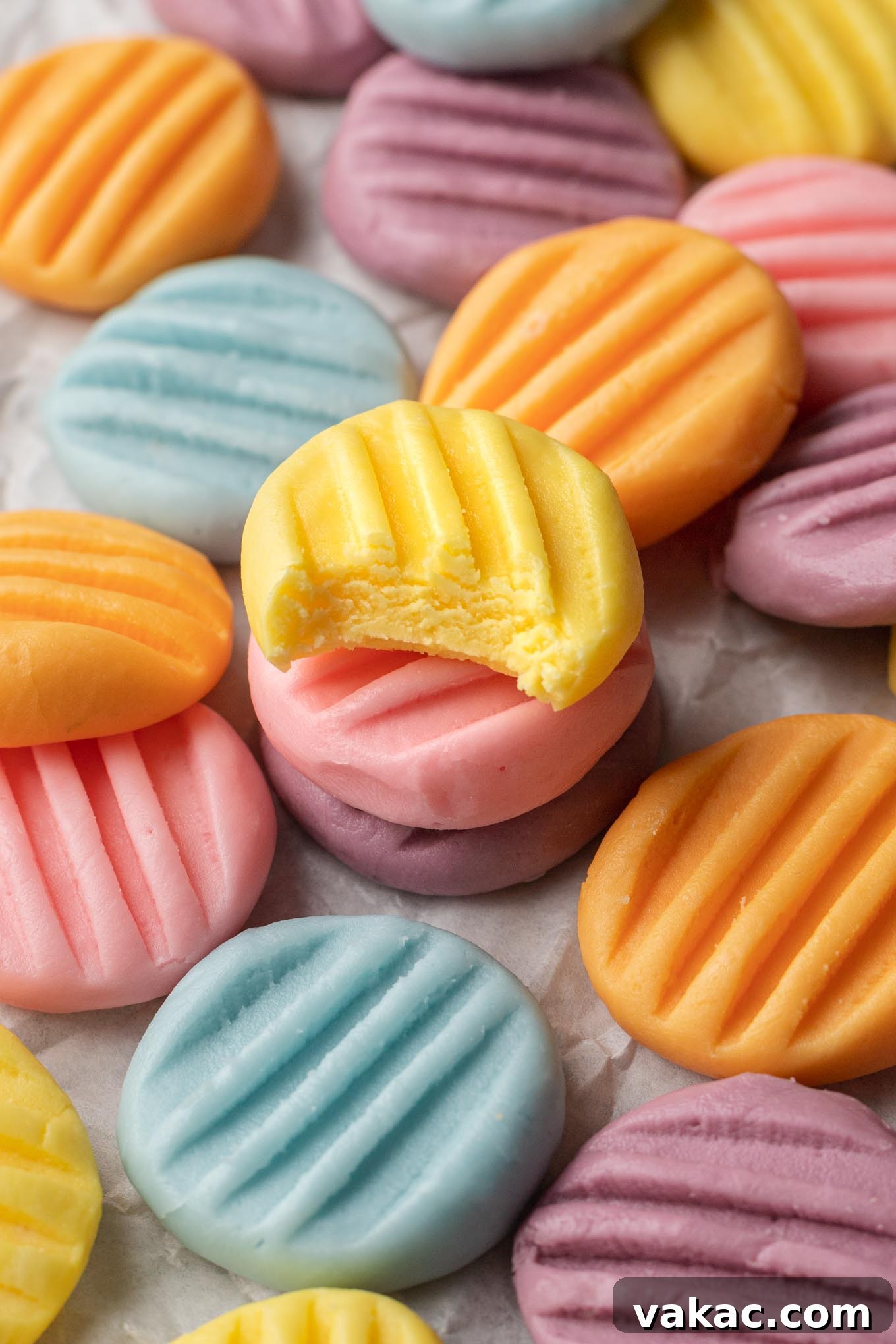 A vibrant, up-close view of a collection of pastel-colored cream cheese mints, beautifully scattered over parchment paper, highlighting their delicate textures and soft hues.