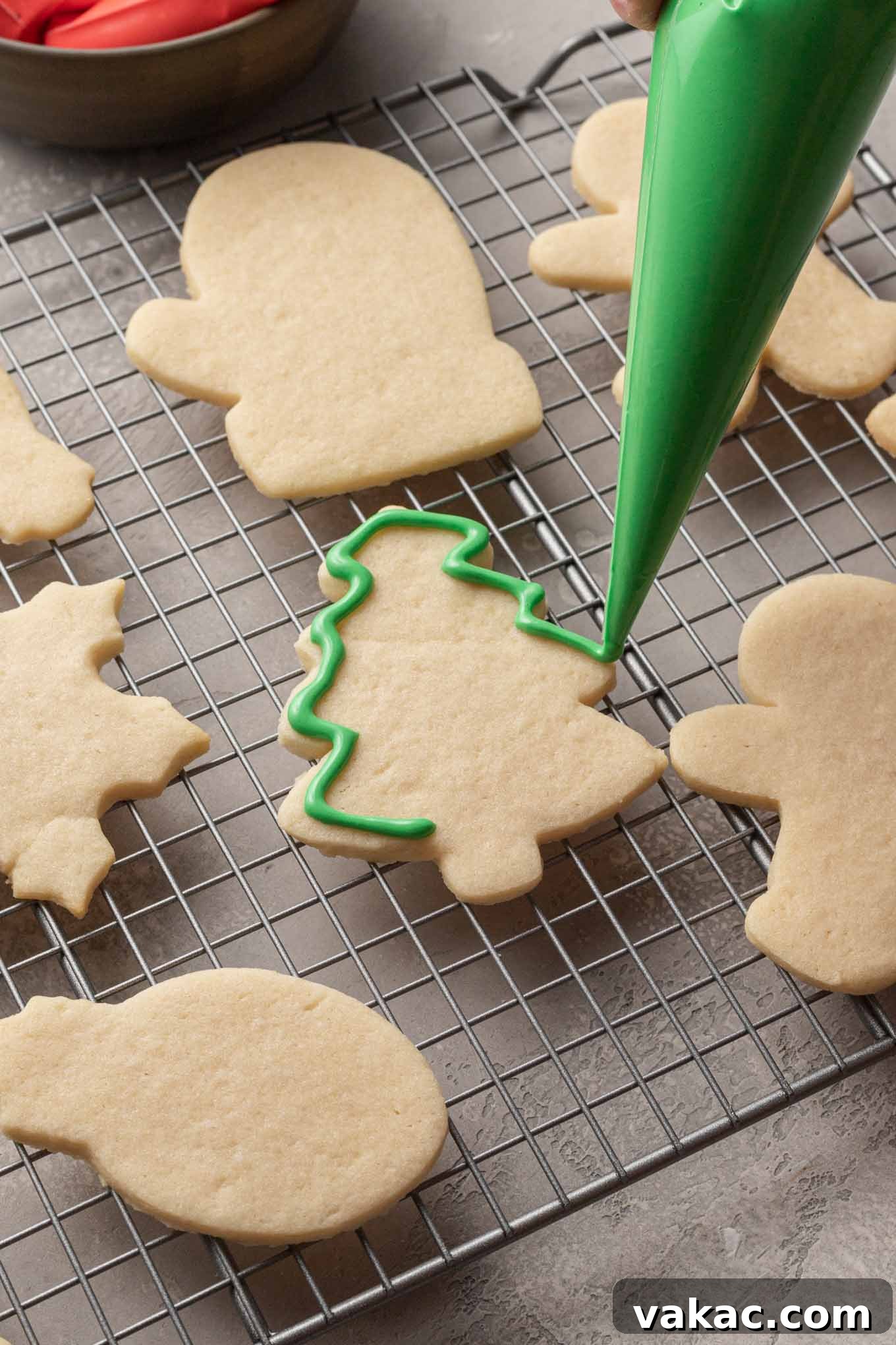 A tree shaped sugar cookie being outlined with green royal icing.