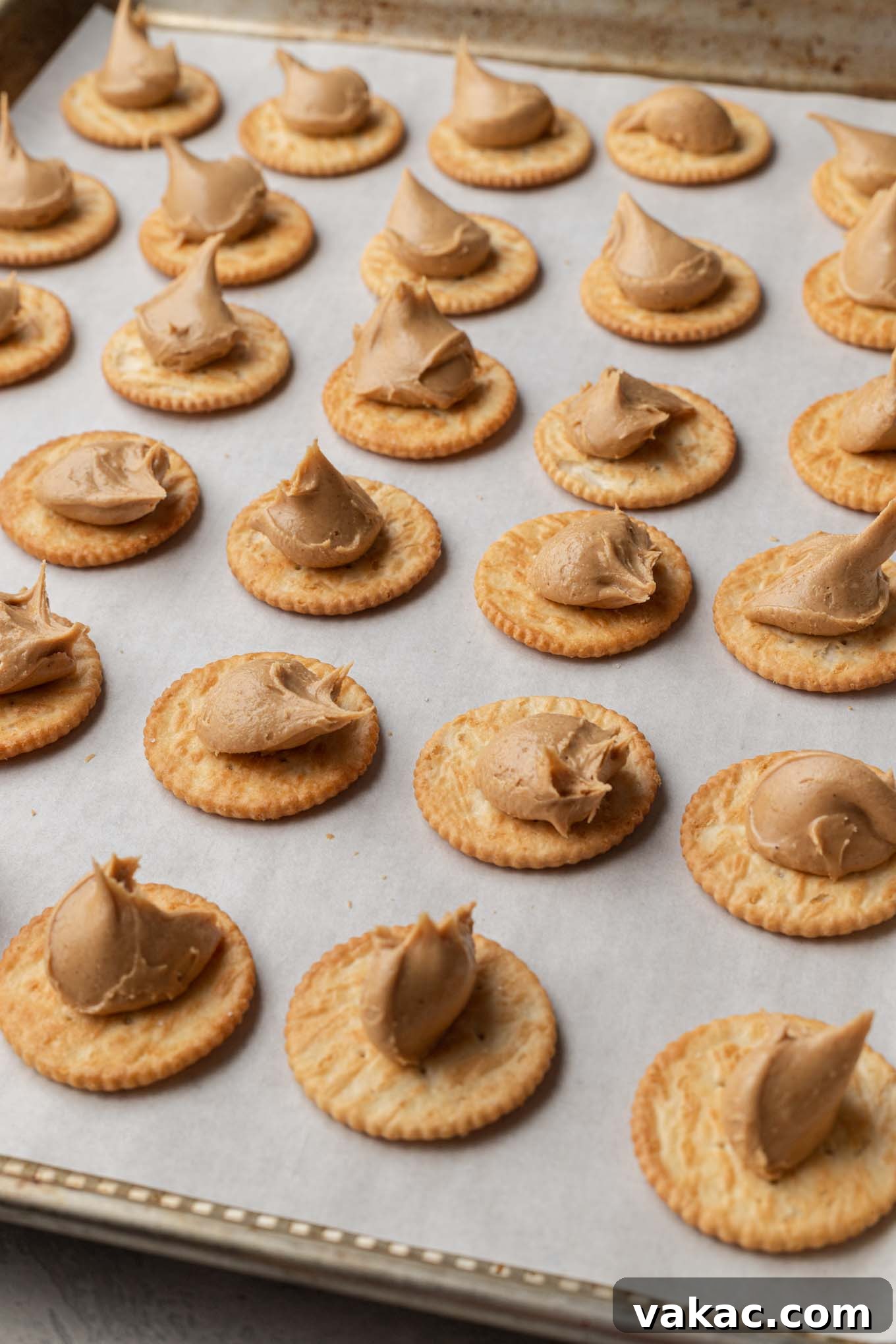 Golden Ritz Delights 6 Rows of Ritz crackers on a baking sheet, each with a dollop of peanut butter filling in the center.