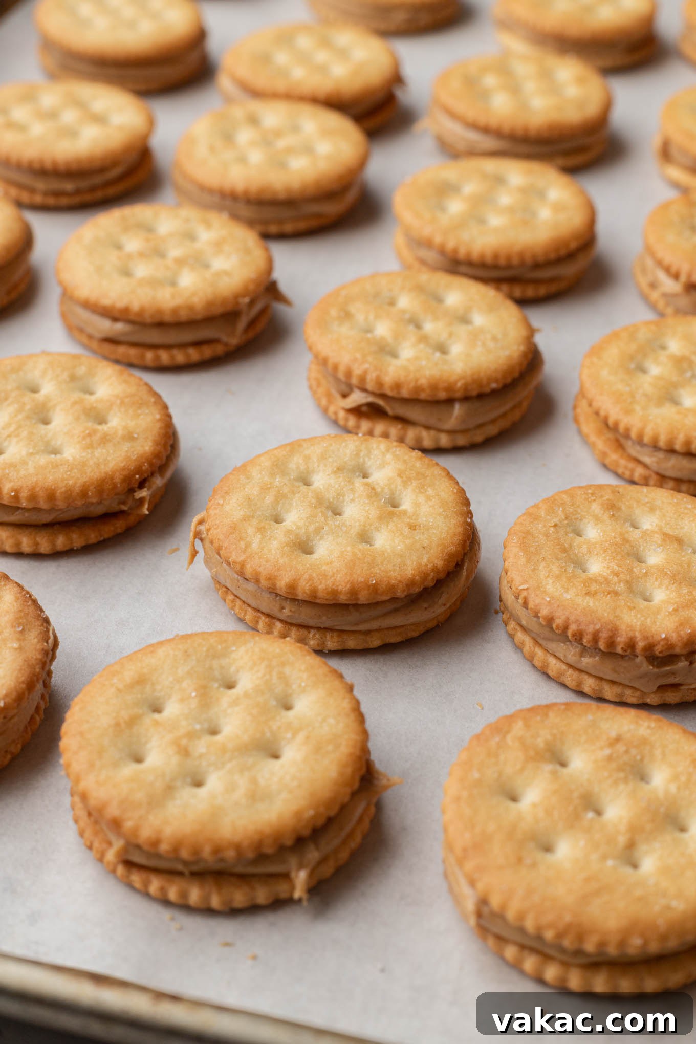 Golden Ritz Delights 7 Rows of finished Ritz cracker and peanut butter sandwiches, lined up on a baking sheet, ready for chilling and dipping.