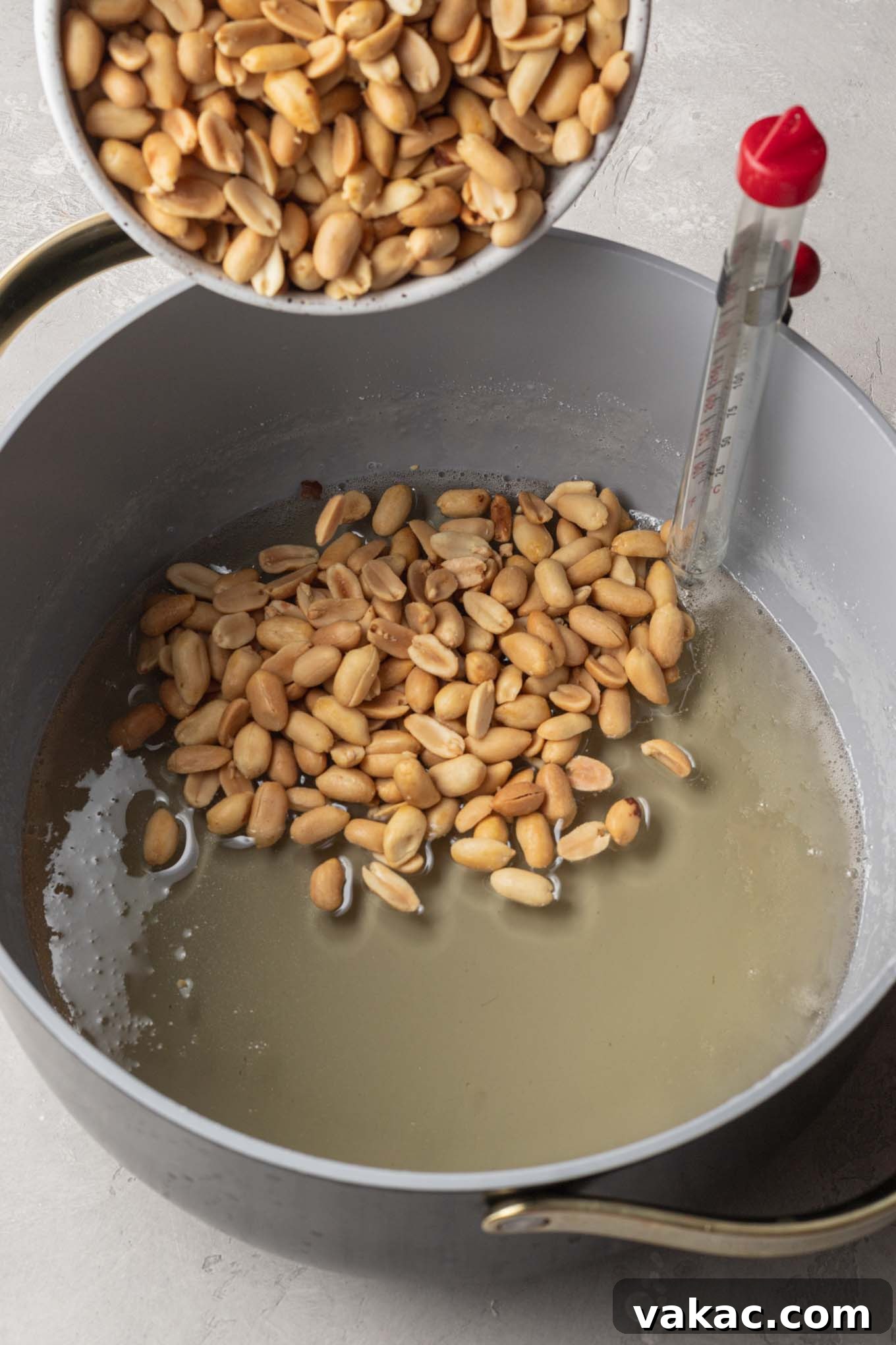 Sweet Peanut Crunch 5 An overhead view of peanuts being mixed into a cooked brittle mixture in a saucepan.