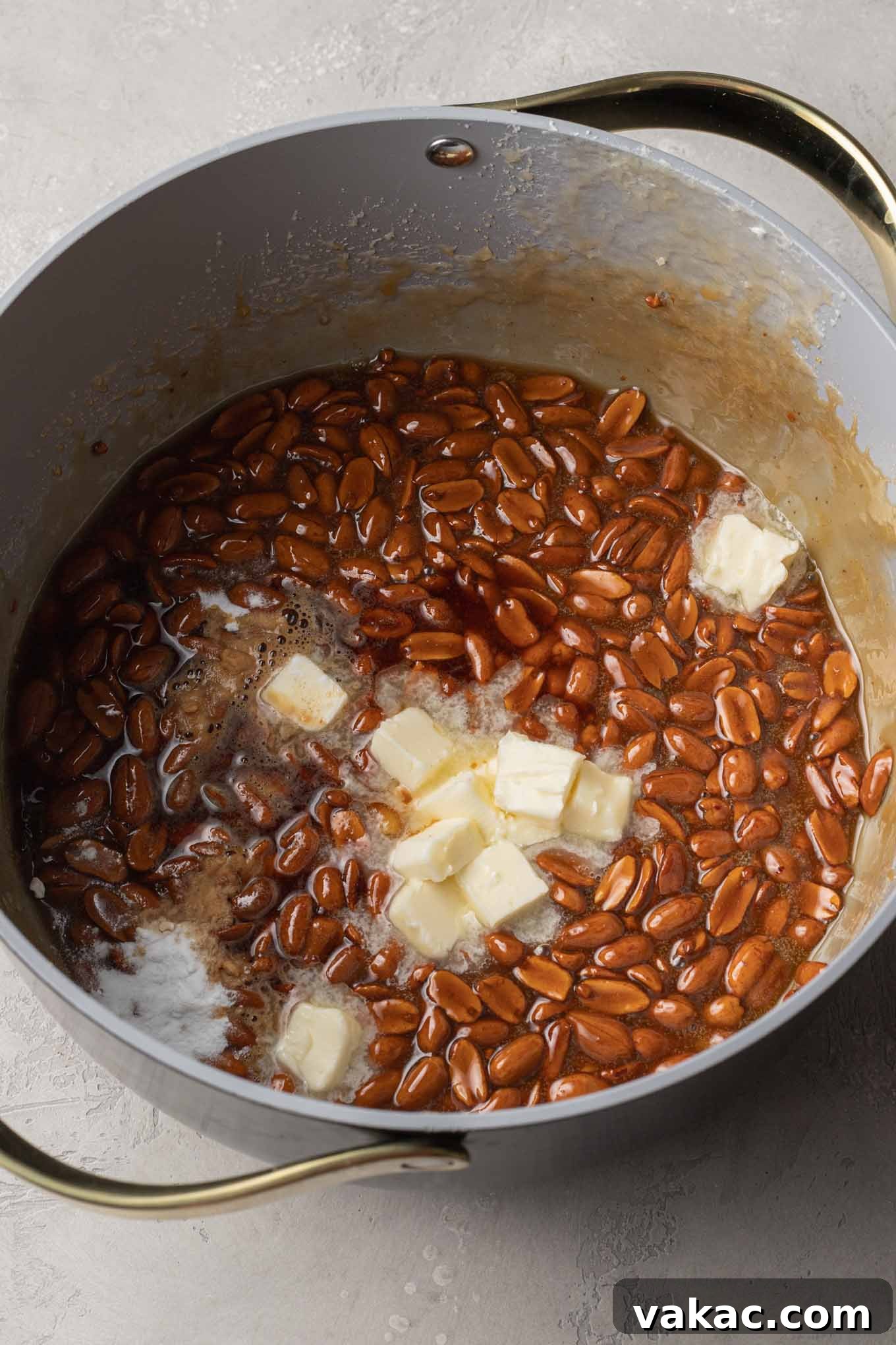 Sweet Peanut Crunch 6 An overhead view of butter being added to a saucepan of peanut brittle.