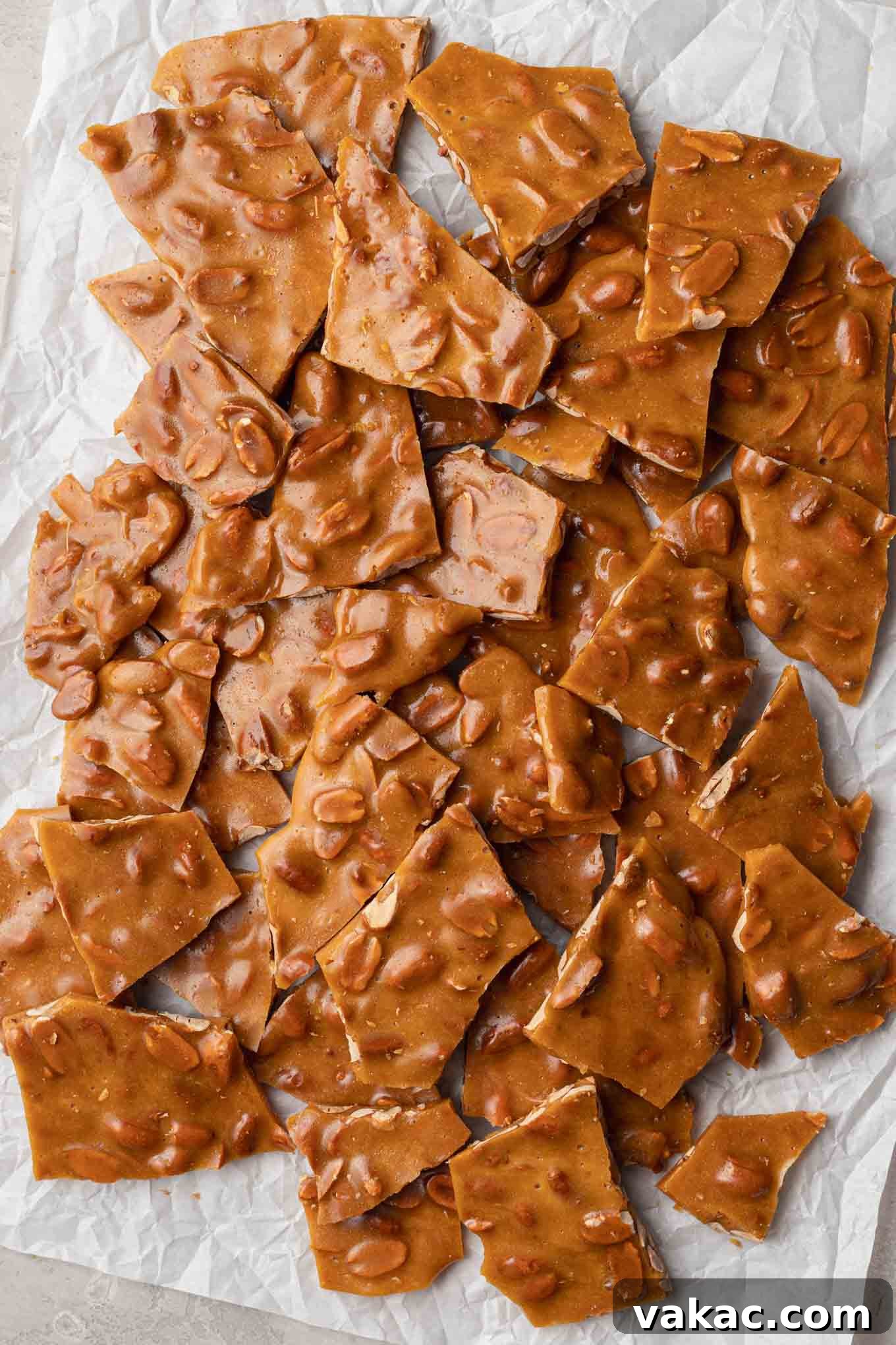 Sweet Peanut Crunch 8 An overhead view of peanut brittle broken into pieces on a piece of parchment paper.