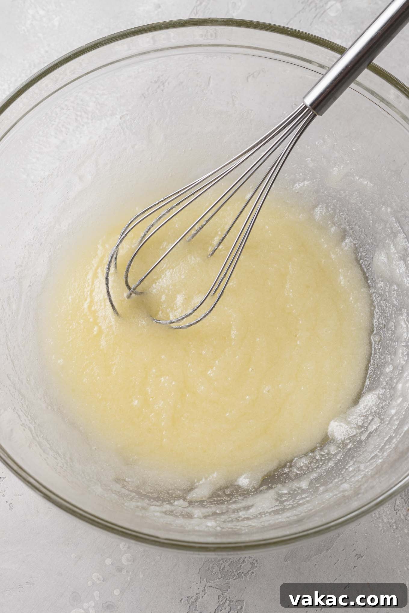 Bite-Sized Brownie Bliss 4 An overhead view of melted butter and sugar in a glass mixing bowl with a whisk.