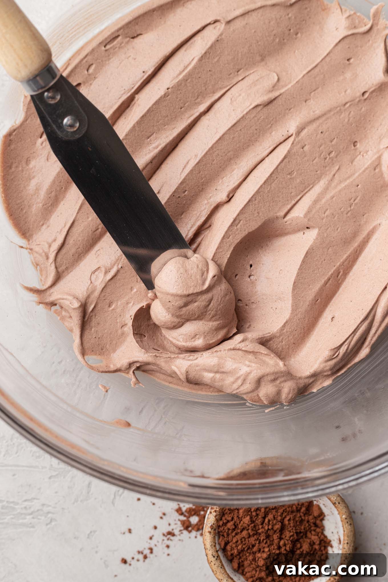 Velvet Chocolate Whip 7 A glass mixing bowl filled with the finished chocolate whipped cream. An angled spatula is resting inside of the bowl.