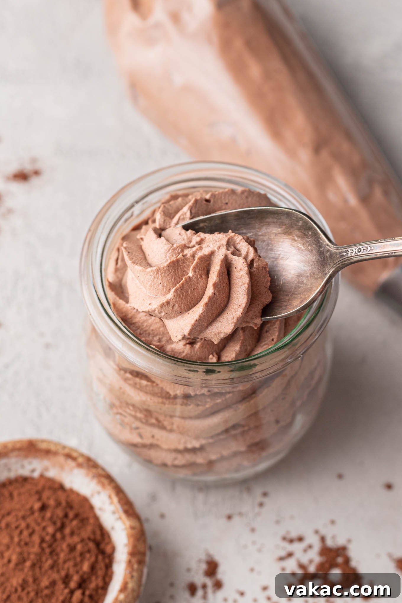 Velvet Chocolate Whip 8 A small jar filled with chocolate whipped cream. A spoon is taking a small scoop out of the whipped cream.