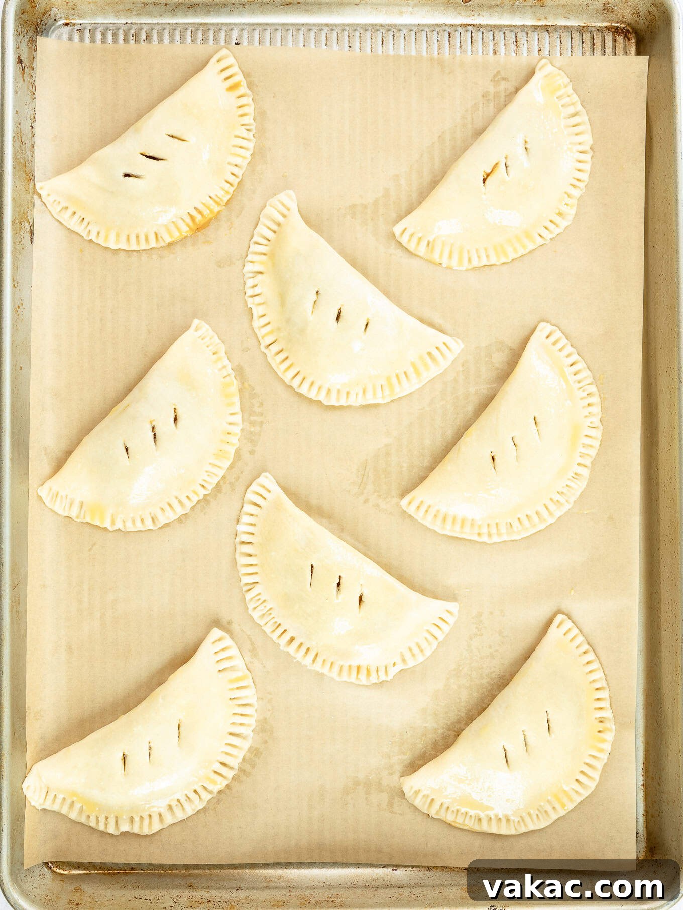 Autumn Pumpkin Pockets 8 A collection of unbaked pumpkin hand pies, neatly arranged on a parchment-lined baking sheet, chilling before their oven debut.