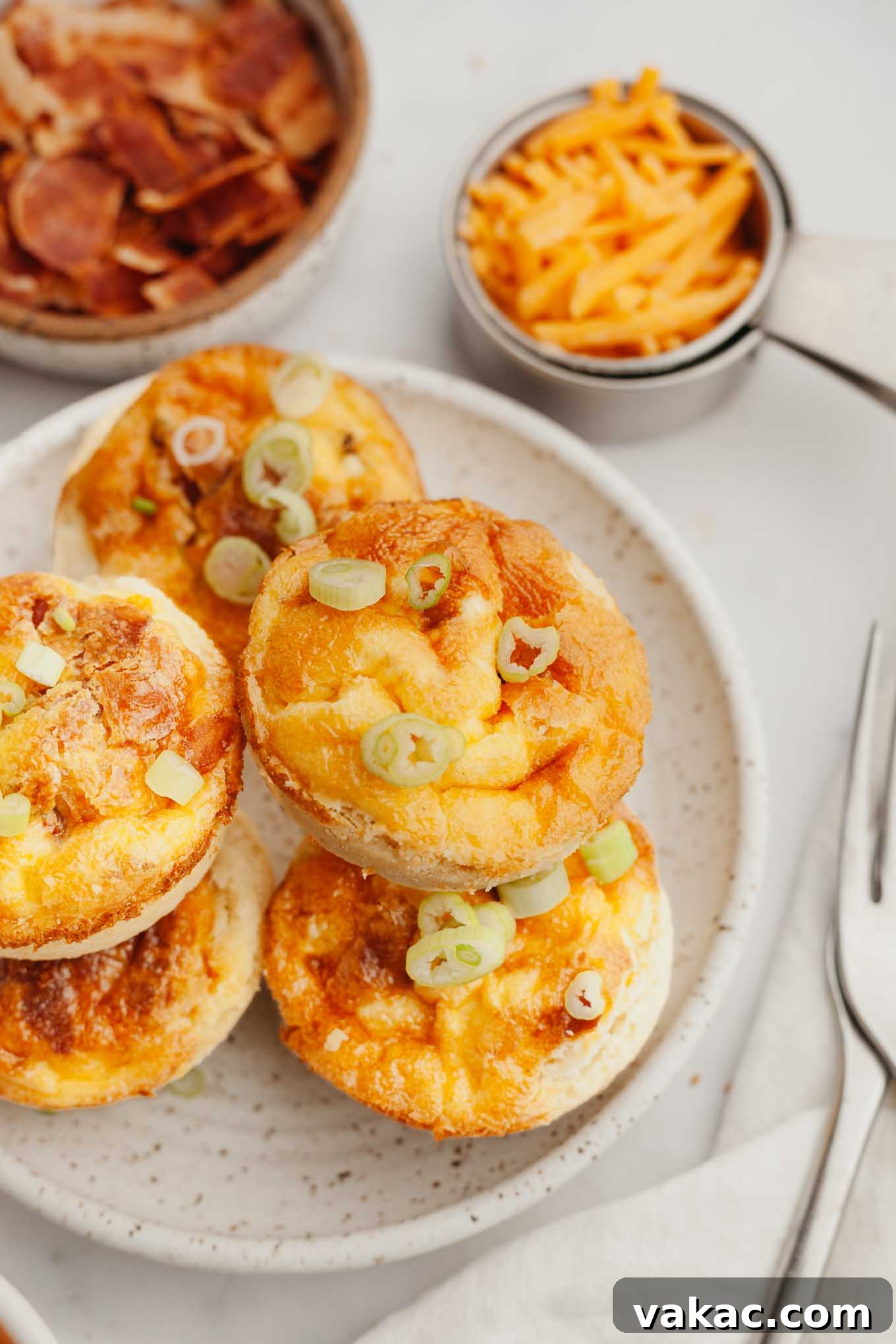 Bite-Sized Quiche Delights 2 A stack of golden-brown mini quiches on a speckled white plate, ready to be served for breakfast or brunch.