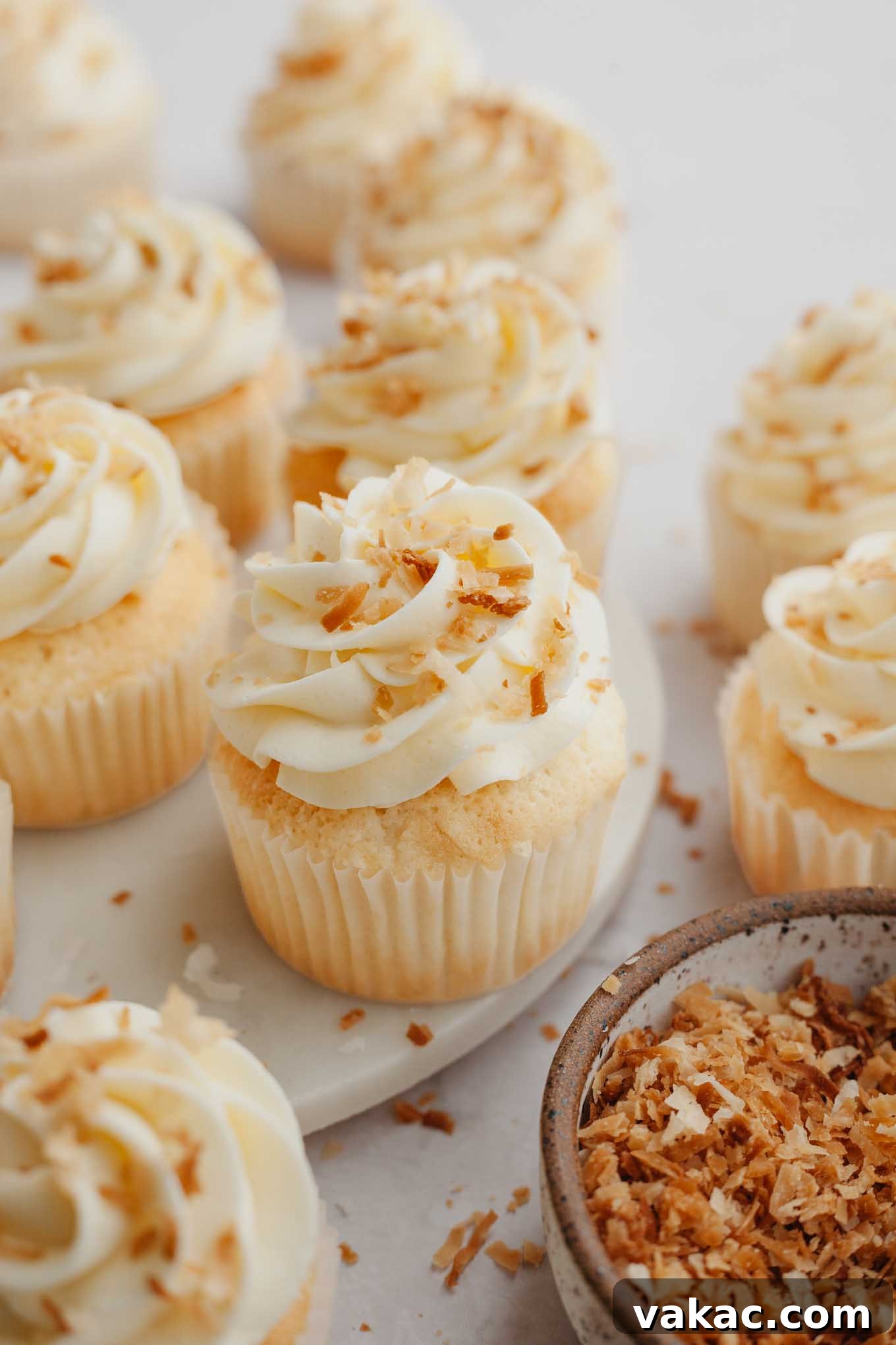 Tropical Coconut Delights 2 Soft and fluffy coconut cupcakes topped with creamy coconut frosting and toasted coconut flakes, ready to be enjoyed.