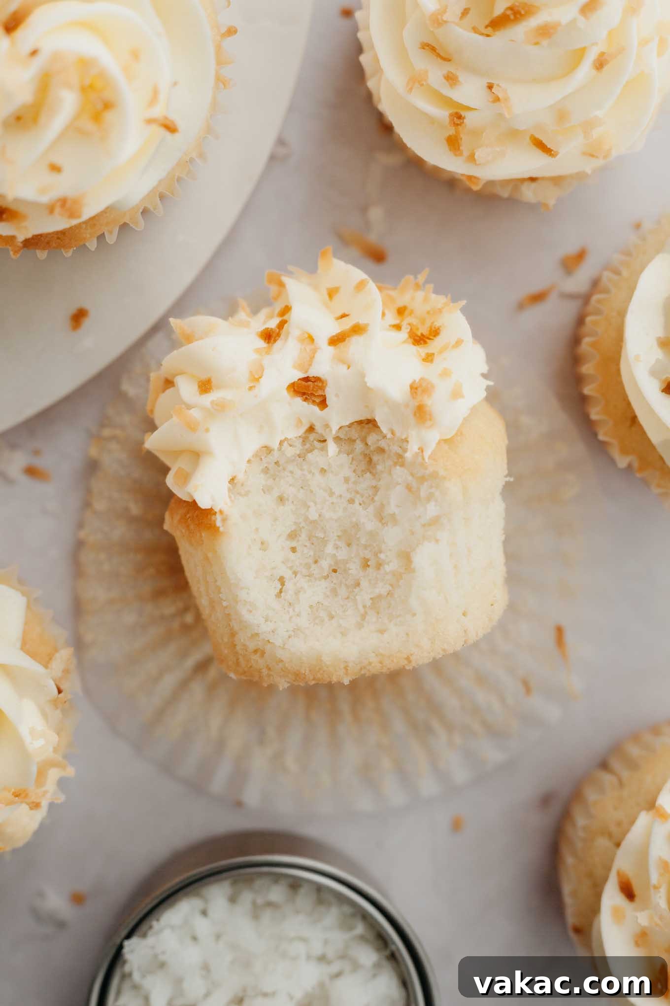 Tropical Coconut Delights 12 An overhead view of a single coconut cupcake, beautifully frosted and garnished, lying on its side on a plate, highlighting its perfect texture.
