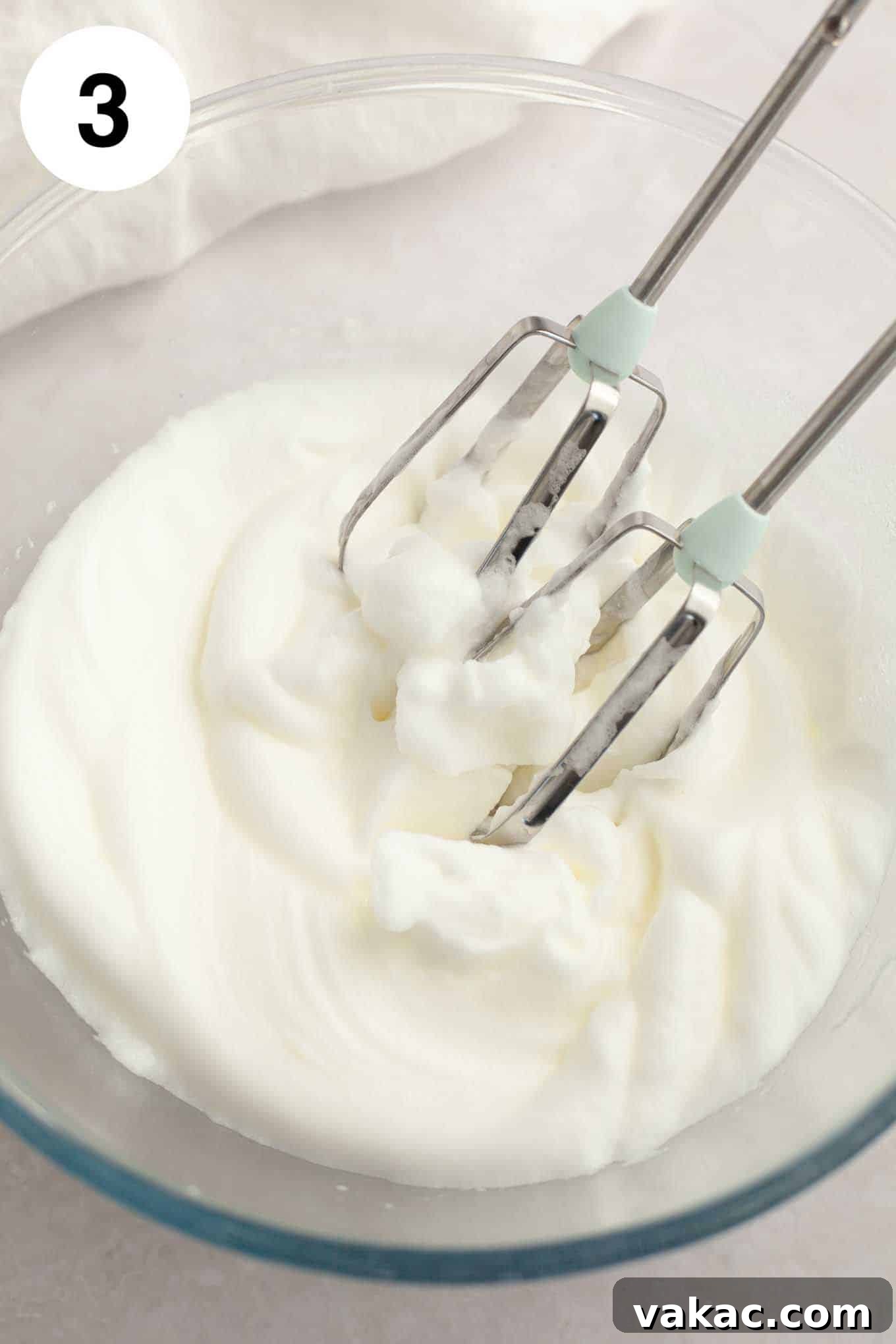 Tropical Coconut Delights 7 An overhead view of perfectly whipped egg whites forming stiff peaks in a pristine glass mixing bowl, indicating they are ready to be folded into the batter.