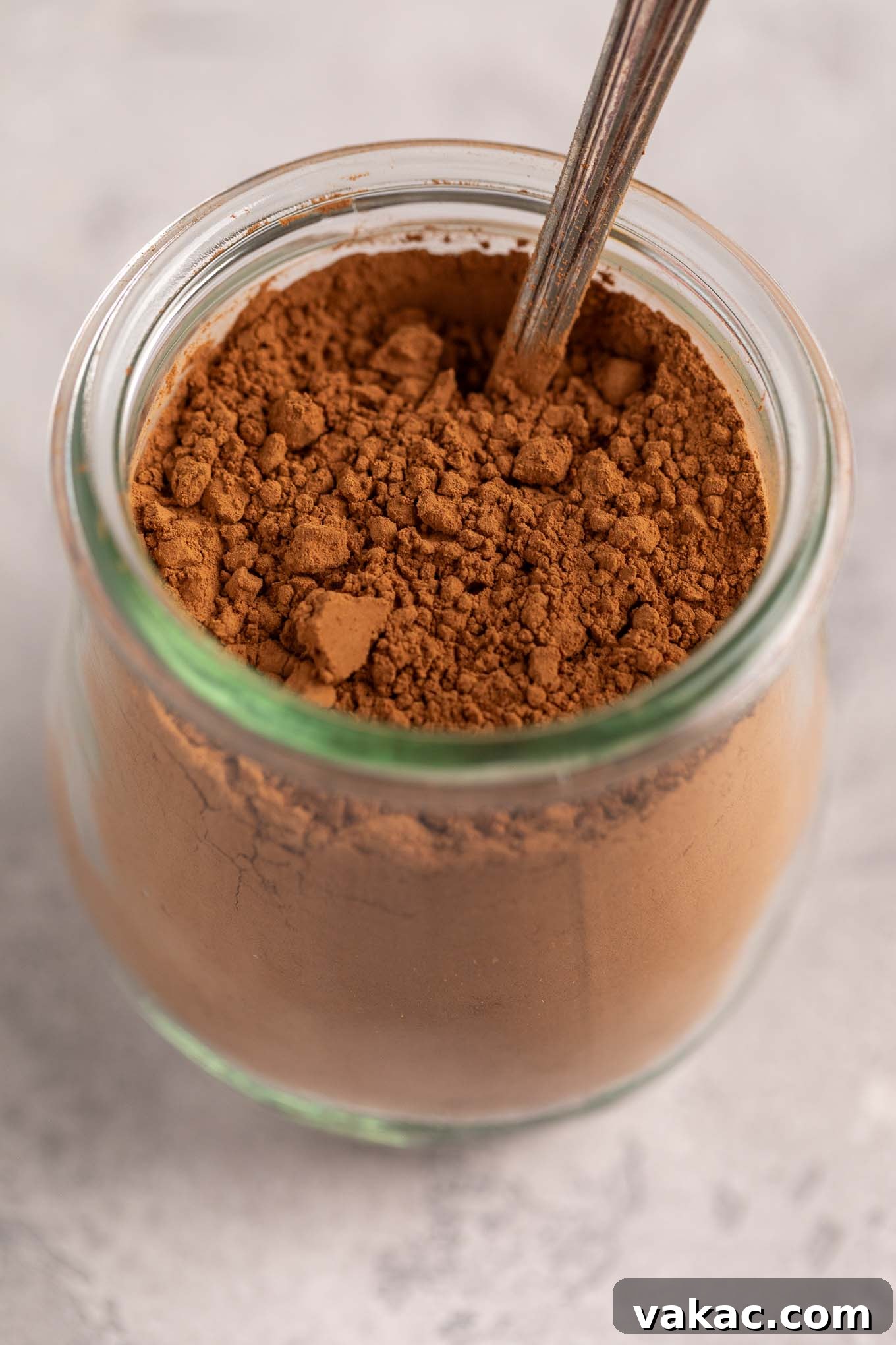 Natural vs. Dutch Process Cocoa: The Baker's Choice 2 A small glass jar filled with rich cocoa powder, with a measuring spoon resting inside.