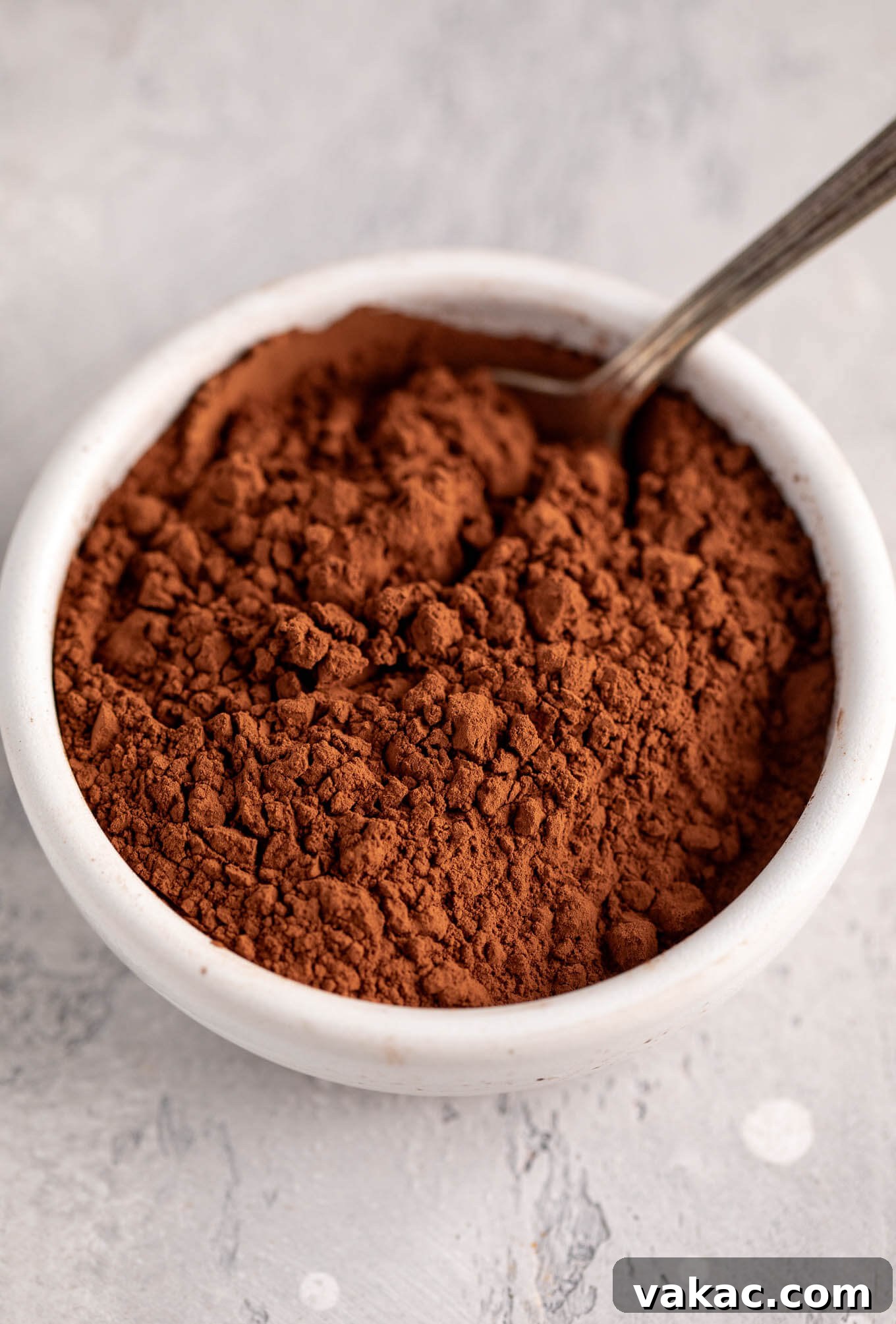 Natural vs. Dutch Process Cocoa: The Baker's Choice 6 A bowl filled with dark, rich Dutch-process cocoa powder, ready for baking, with a spoon nestled within.