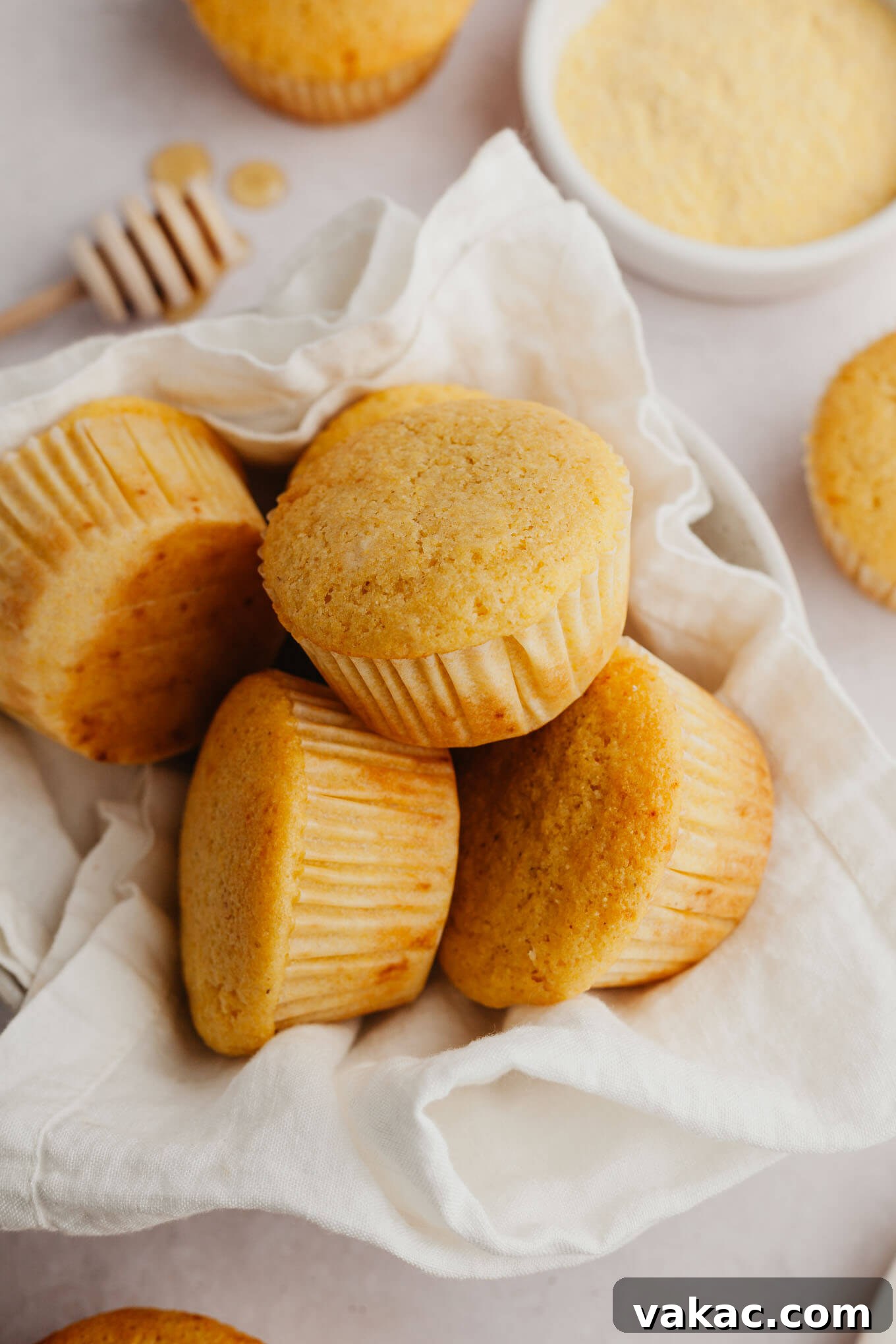 Golden Fluffy Cornbread Muffins 2 A pile of golden-brown cornbread muffins in a towel-lined serving bowl, ready to be enjoyed.