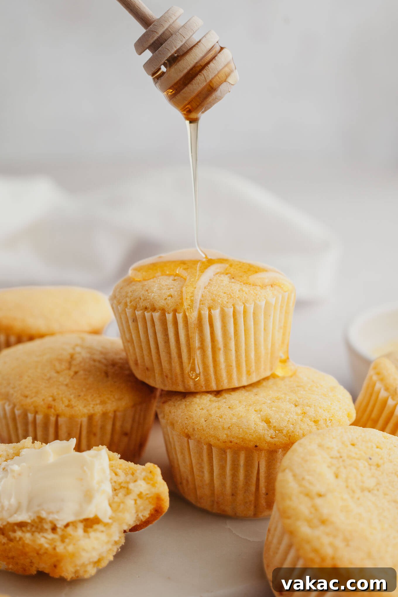 Golden Fluffy Cornbread Muffins 7 An action shot showing golden honey being generously drizzled over a stack of warm, sweet cornbread muffins, highlighting their delicious appeal.