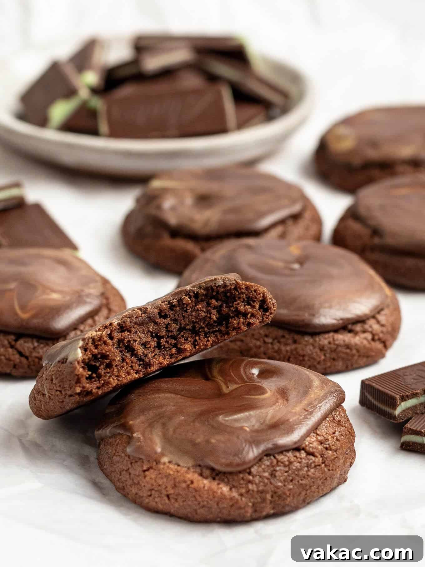 Several Andes mint cookies on a piece of white parchment paper, with a bowl of Andes mints in the background.