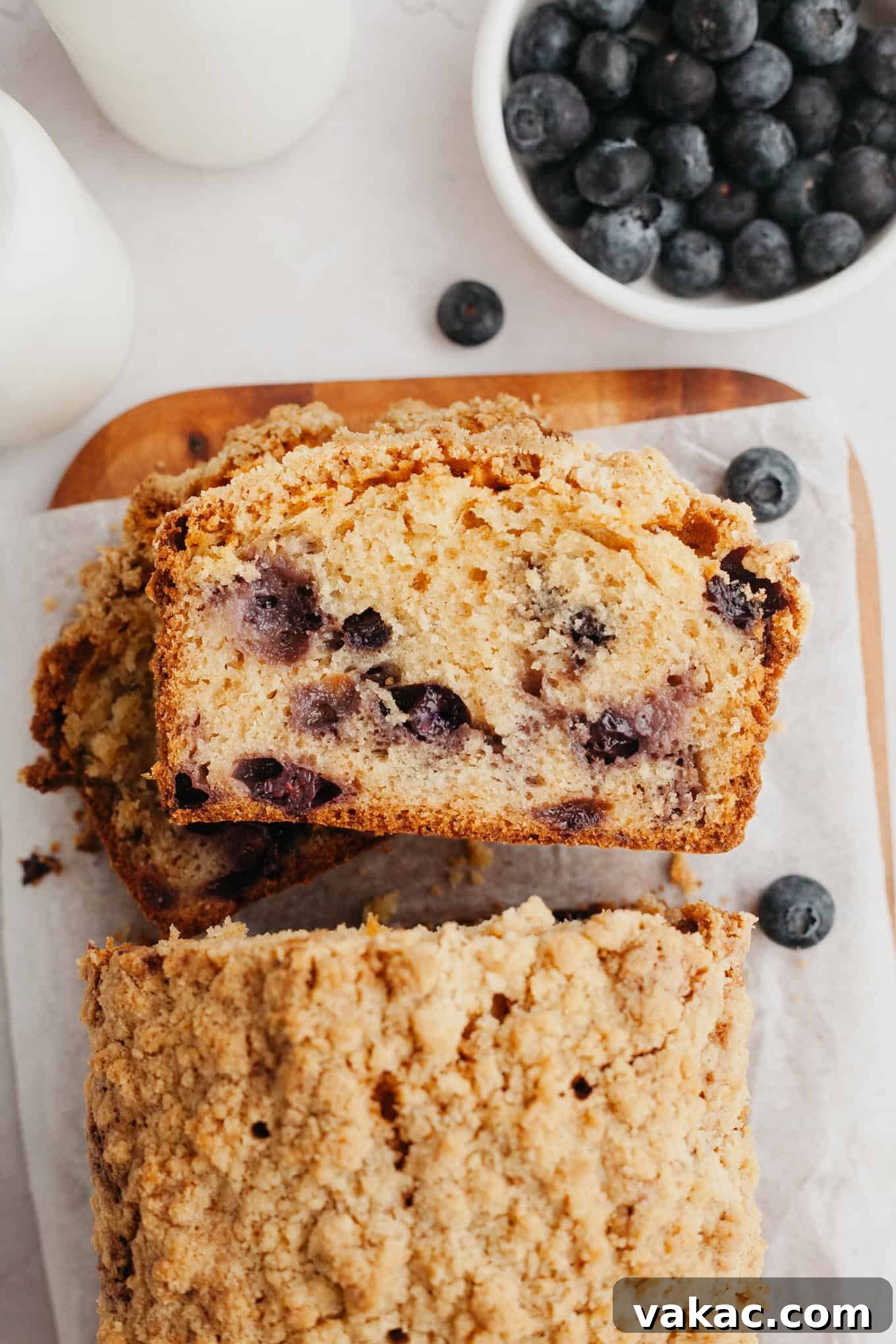Berry Burst Bread 2 An overhead view of several slices of homemade blueberry streusel bread, neatly stacked on their sides, revealing the vibrant blueberries within and the golden, crumbly streusel topping.