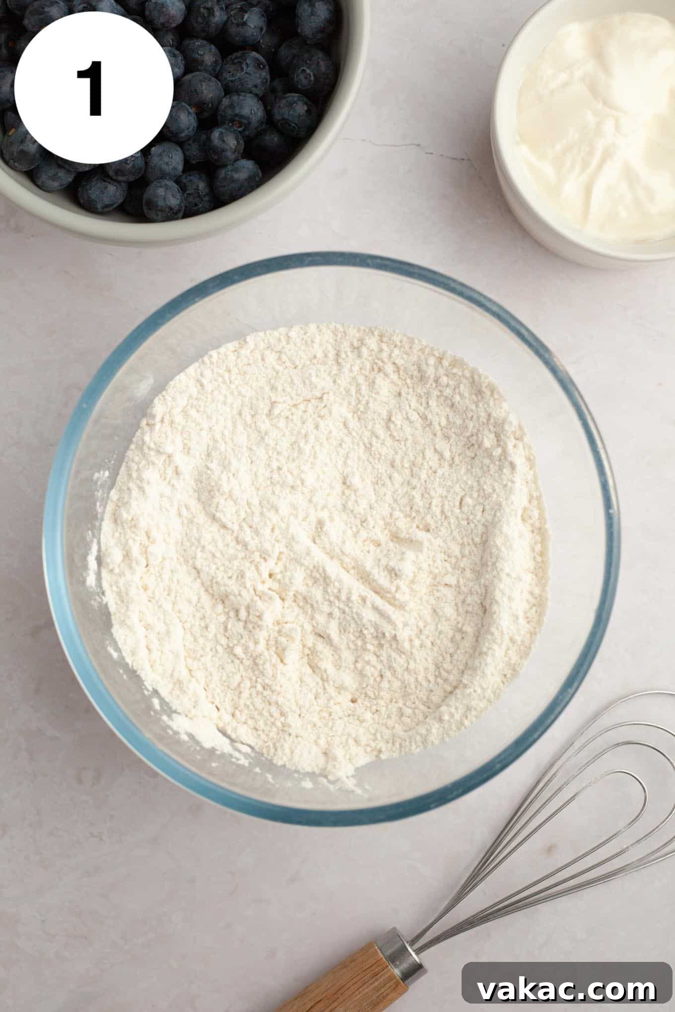 Berry Burst Bread 4 An overhead view of a flour mixture, carefully combined with baking powder, baking soda, and salt, resting in a clear glass mixing bowl, representing the essential dry ingredients for the blueberry bread.
