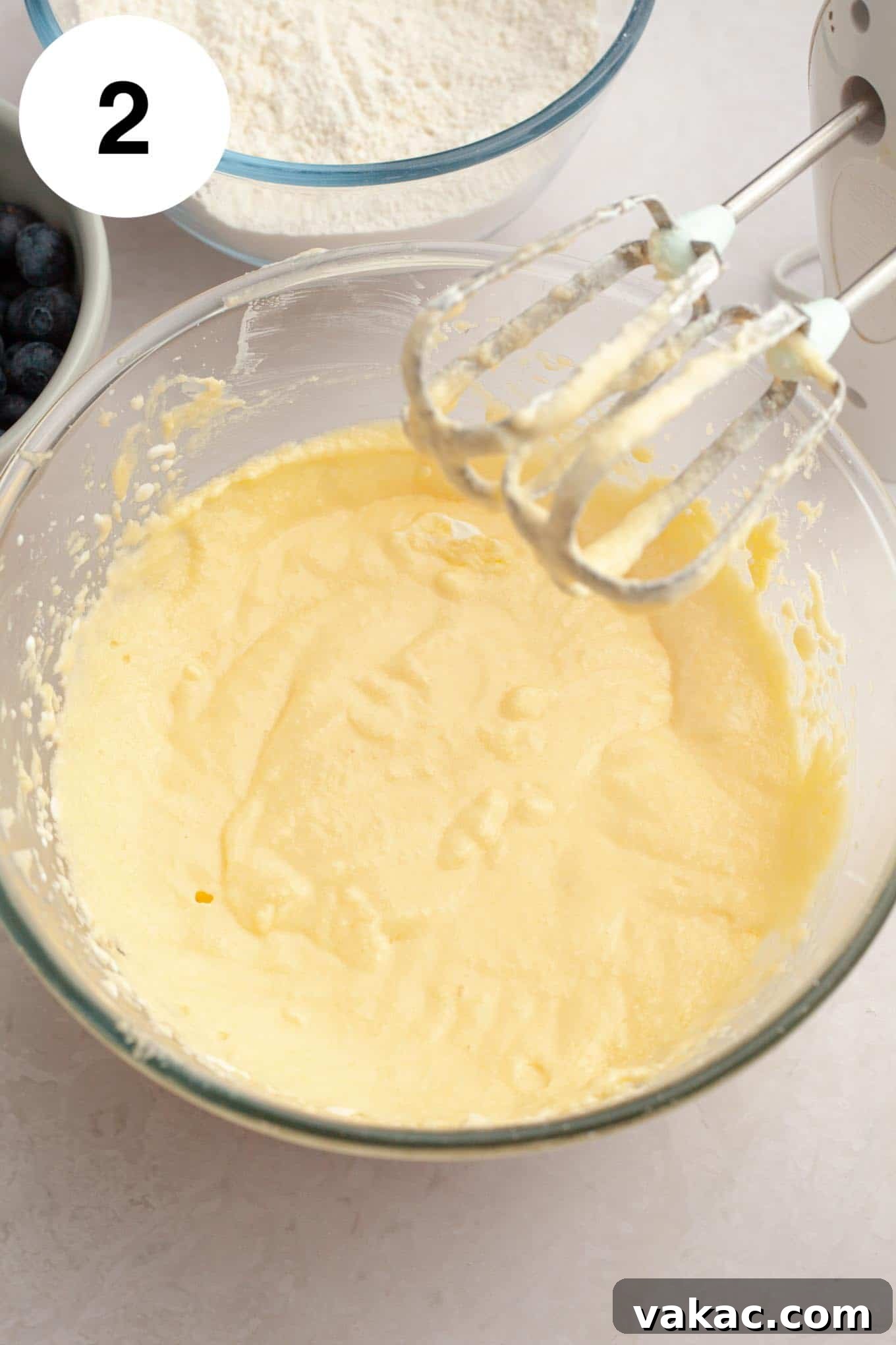 Berry Burst Bread 5 An overhead view of a creamy, light yellow butter and granulated sugar mixture in a glass mixing bowl, with electric beaters resting nearby, indicating the start of the wet ingredient preparation for the bread batter.