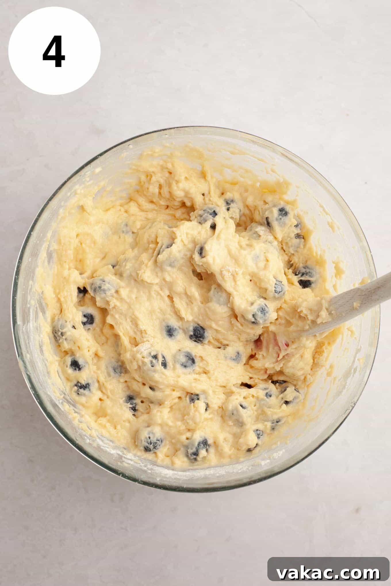 Berry Burst Bread 7 An overhead view of vibrant blueberry bread batter in a glass mixing bowl, with beautiful blueberries gently folded in, creating an appealing contrast of colors and textures, ready for the loaf pan.