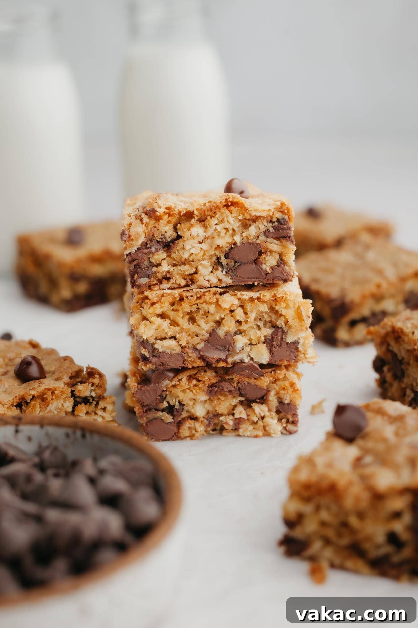 Golden Oatmeal Bars 2 A stack of three golden-brown oatmeal chocolate chip cookie bars, showcasing their soft interior and melted chocolate chips from a side view.