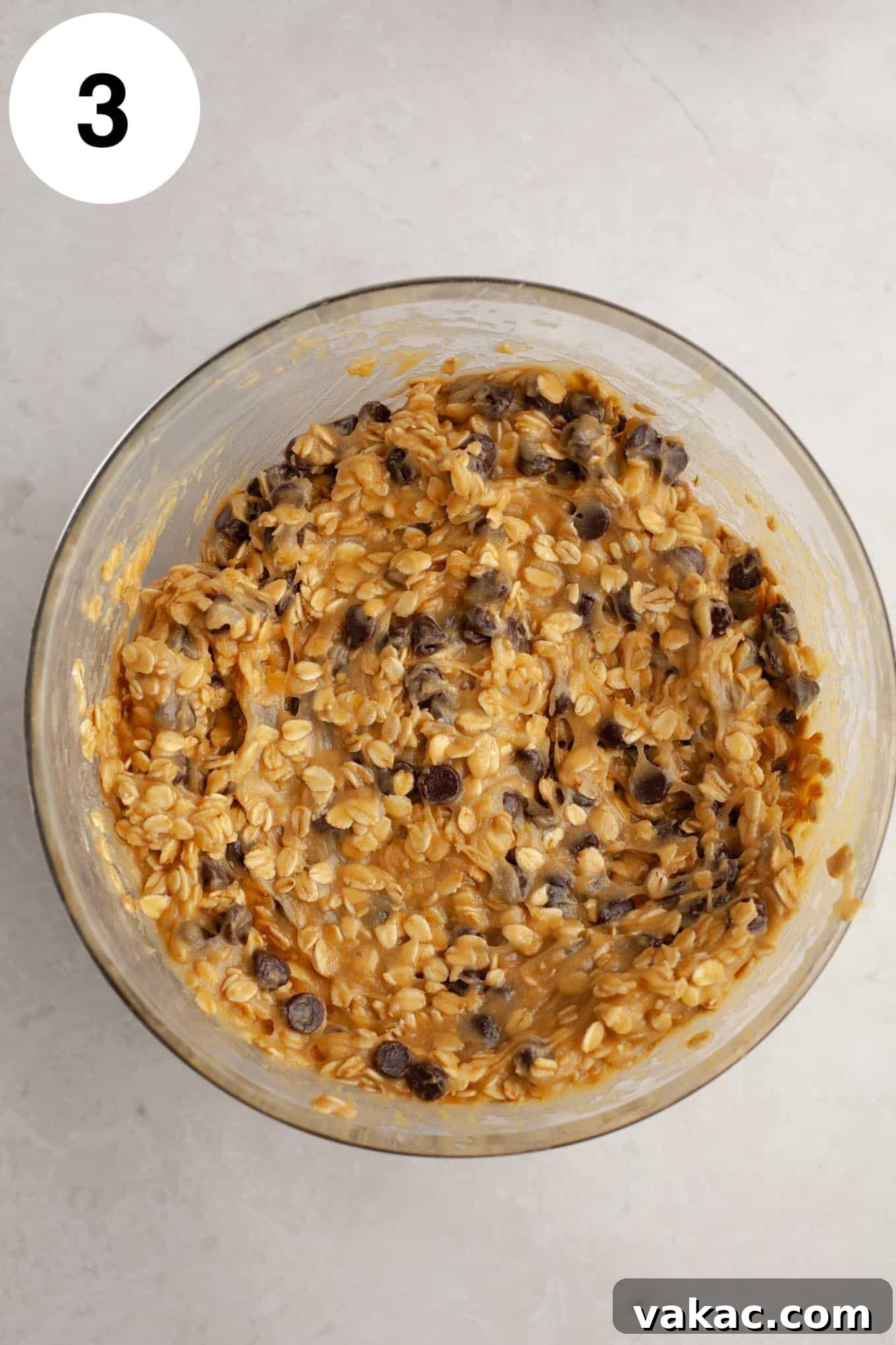 Golden Oatmeal Bars 6 An overhead view of rich oatmeal chocolate chip cookie dough neatly placed in a glass mixing bowl, ready for baking.