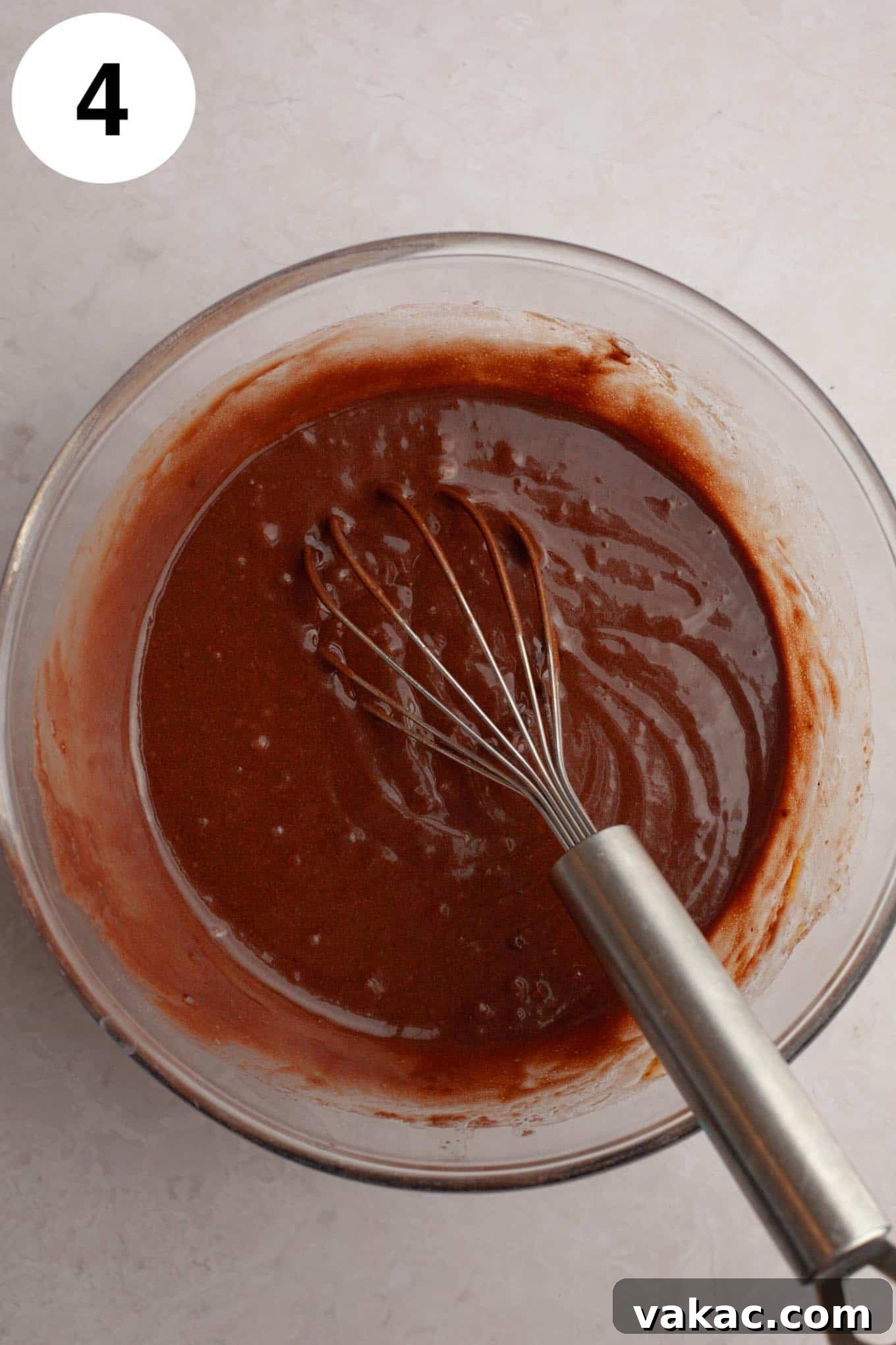 Ultimate German Chocolate Cupcakes 8 An overhead view of the wet ingredients for chocolate cupcakes in a glass mixing bowl, with a whisk.