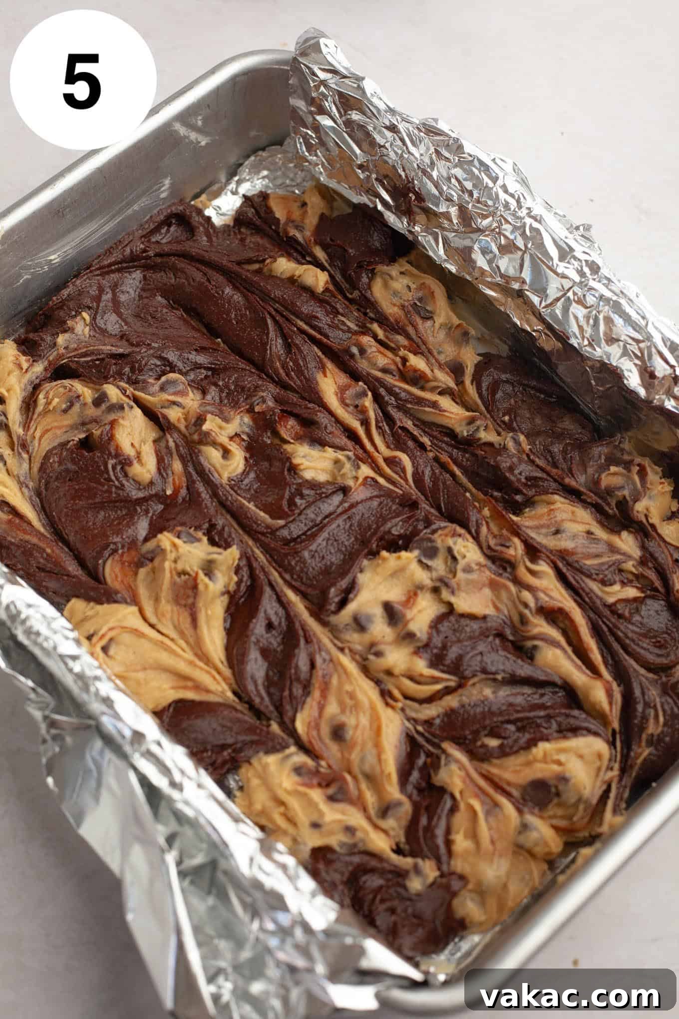 An overhead view of raw brookie batter in a foil-lined pan. 