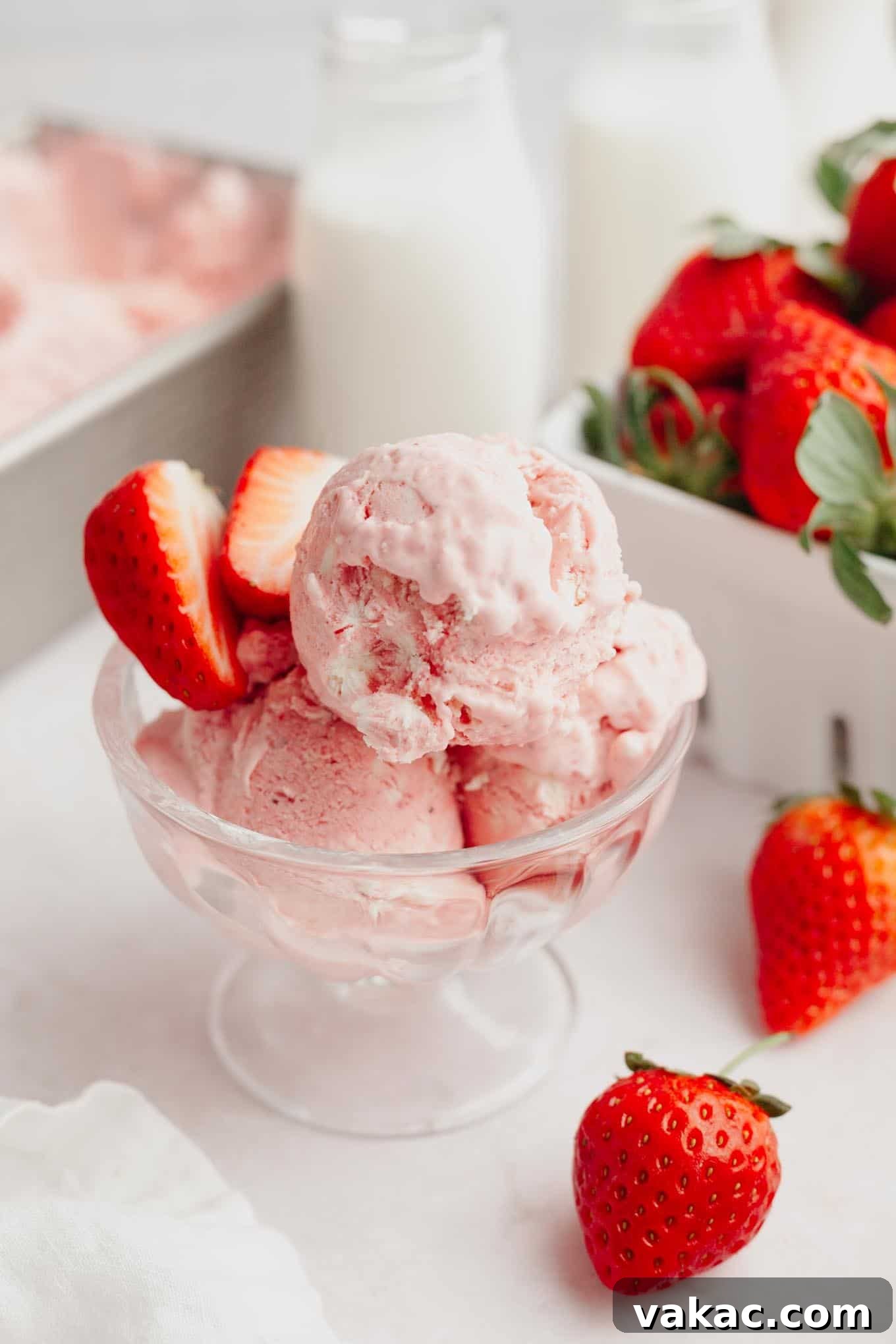 Strawberry Dream Cream 2 Three scoops of vibrant, homemade no-churn strawberry ice cream in an elegant ice cream dish, garnished with fresh mint.