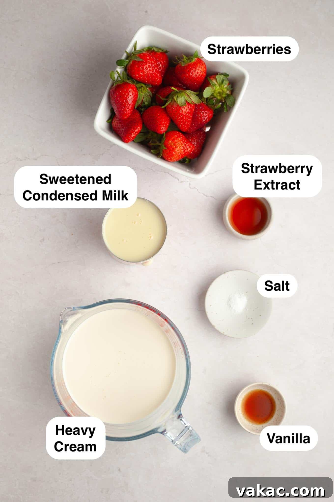 Strawberry Dream Cream 3 An overhead view of the essential ingredients laid out on a clean surface, ready to be transformed into homemade strawberry ice cream: fresh strawberries, a can of sweetened condensed milk, vanilla extract, strawberry extract, salt, and heavy whipping cream.