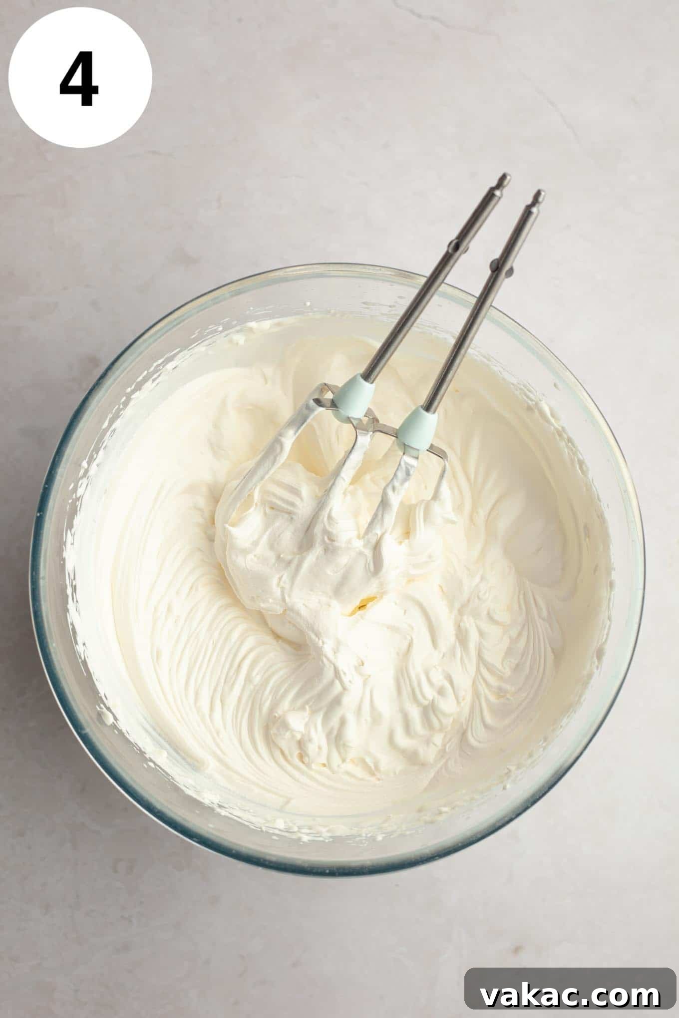 Strawberry Dream Cream 7 An overhead view of perfectly whipped heavy cream in a glass mixing bowl, with electric beaters resting beside it, indicating stiff peaks have been achieved.