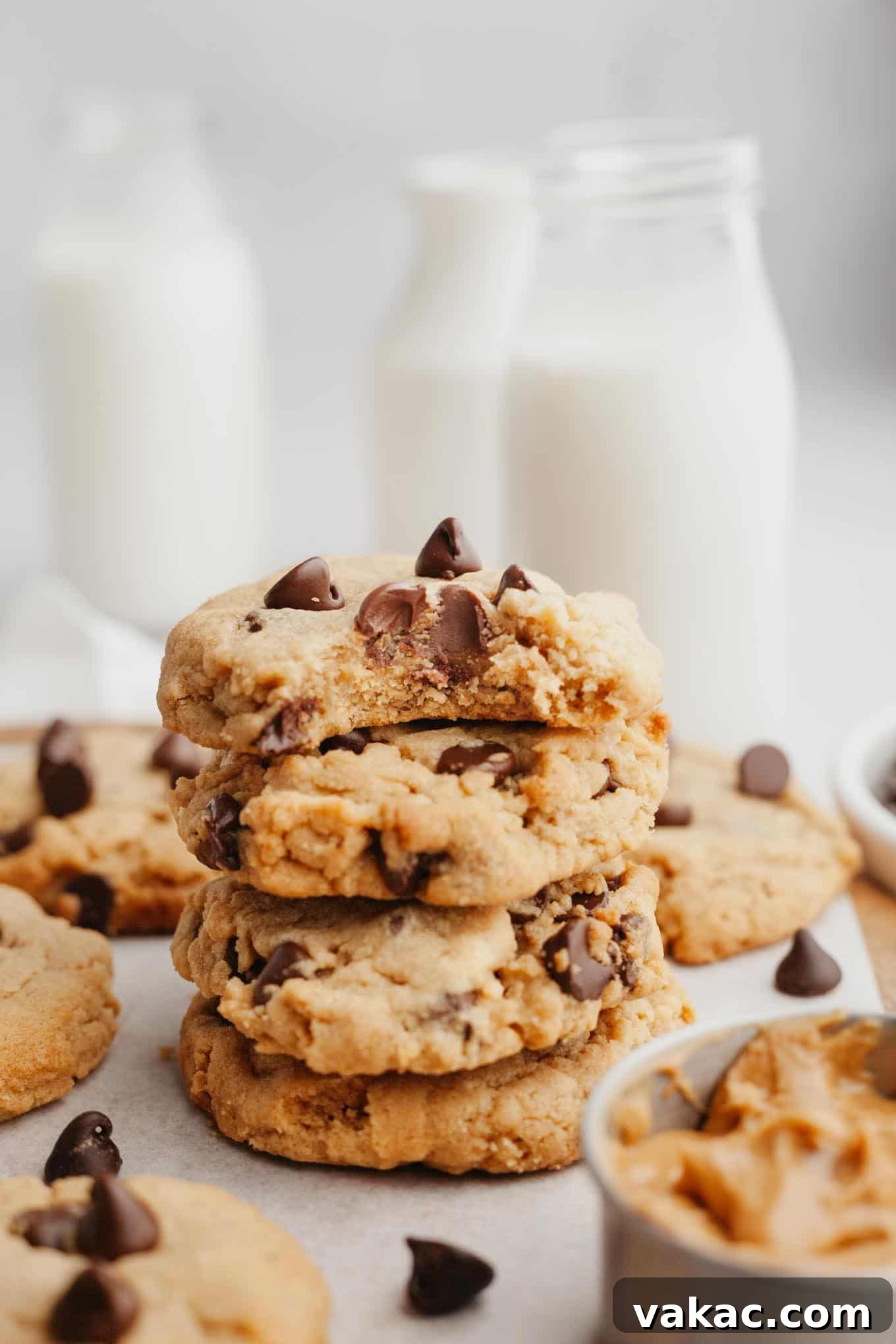 Peanut Butter Chocolate Bliss Bites 2 A stack of four soft, chewy peanut butter chocolate chip cookies; the top cookie has a bite missing, revealing its tender interior and melty chocolate chips.