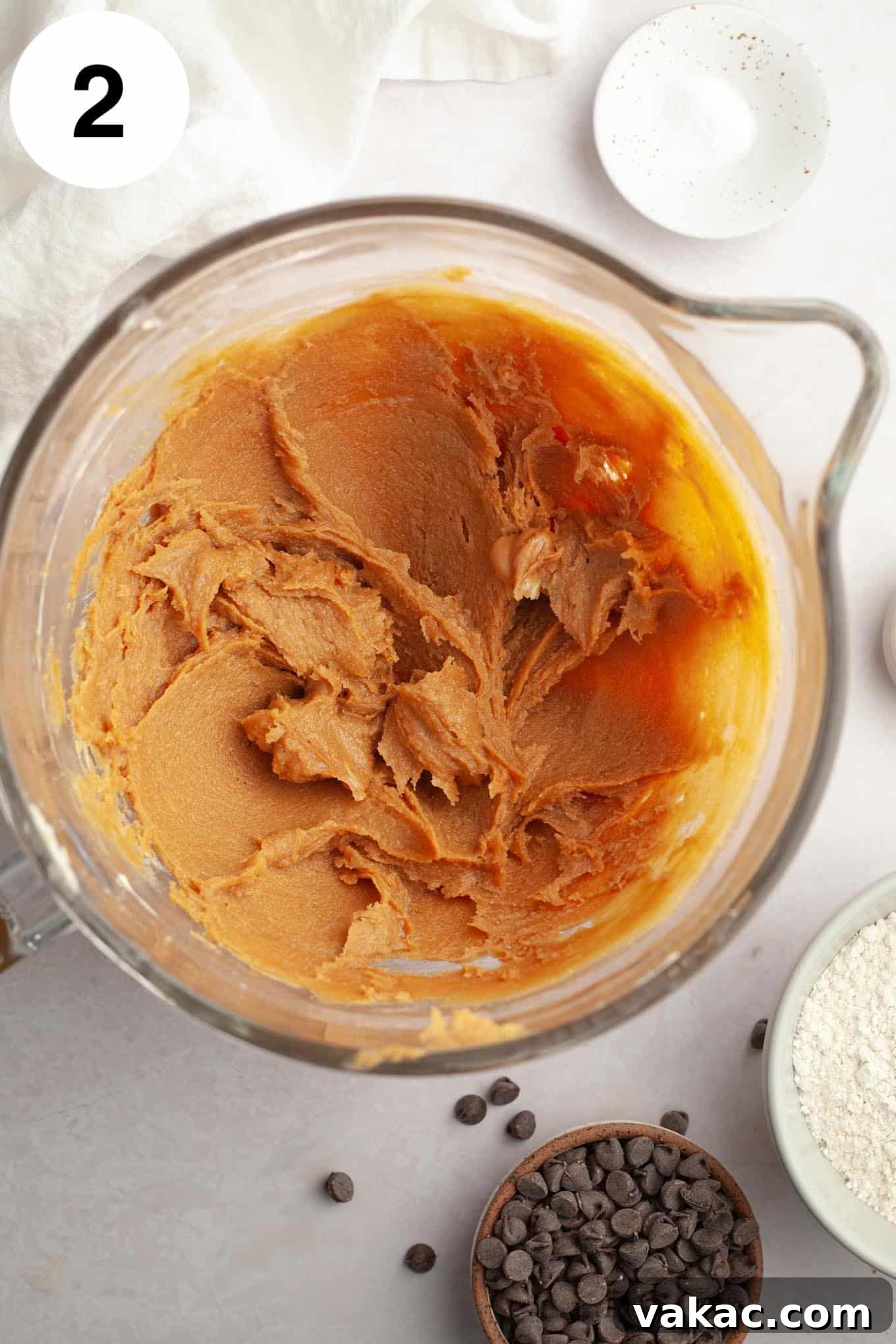 Peanut Butter Chocolate Bliss Bites 5 The next stage in cookie preparation: an overhead view of butter, sugars, and creamy peanut butter blended smoothly in a glass mixing bowl, forming a rich, uniform mixture.