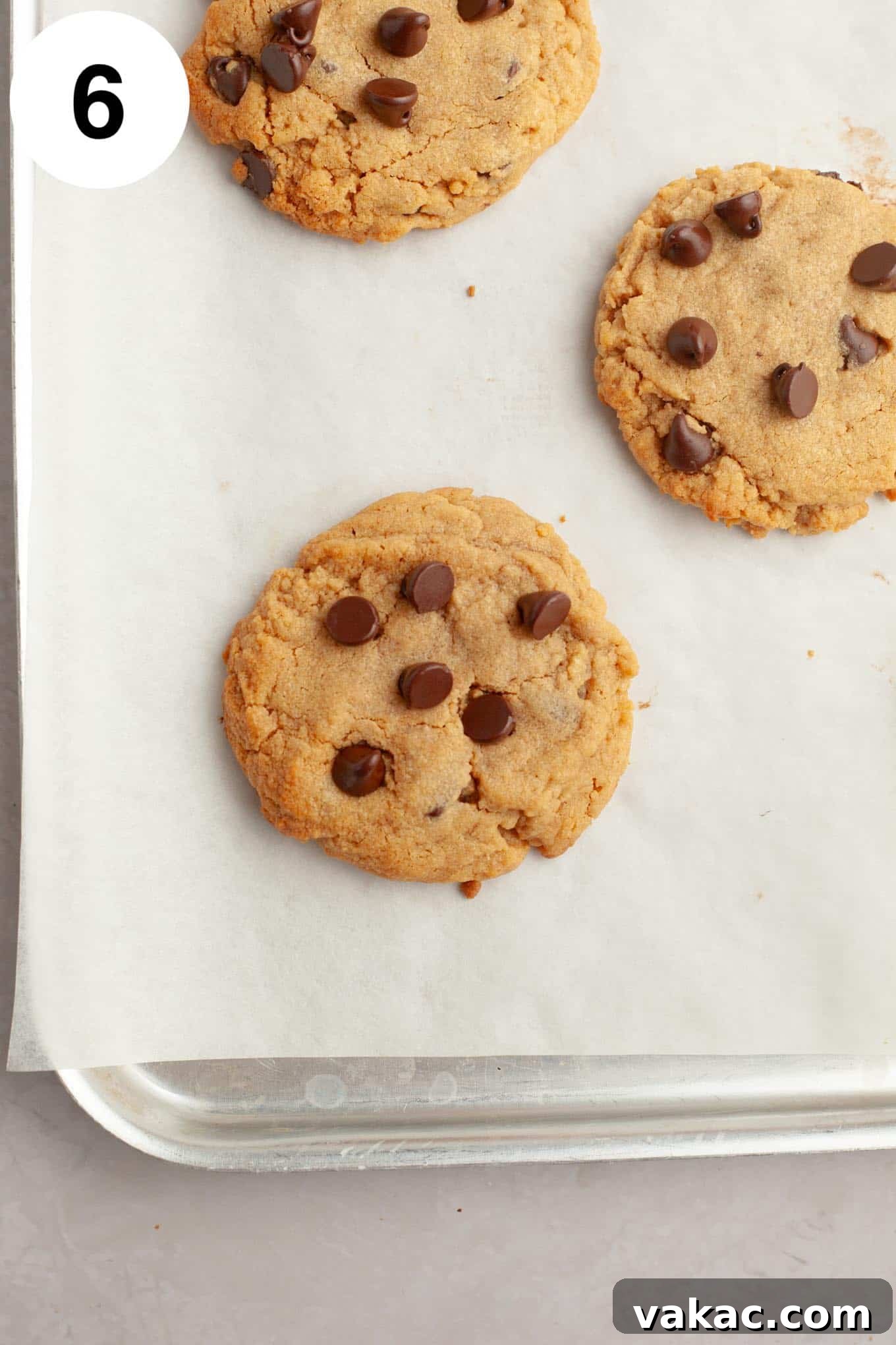 Peanut Butter Chocolate Bliss Bites 9 Freshly baked peanut butter chocolate chip cookies, golden brown and still warm, resting on a parchment paper-lined baking sheet.