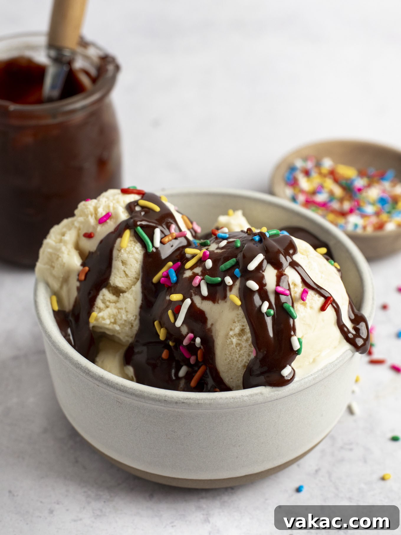 Decadent Homemade Hot Fudge Sauce 2 A dish of ice cream topped with hot fudge and rainbow sprinkles.