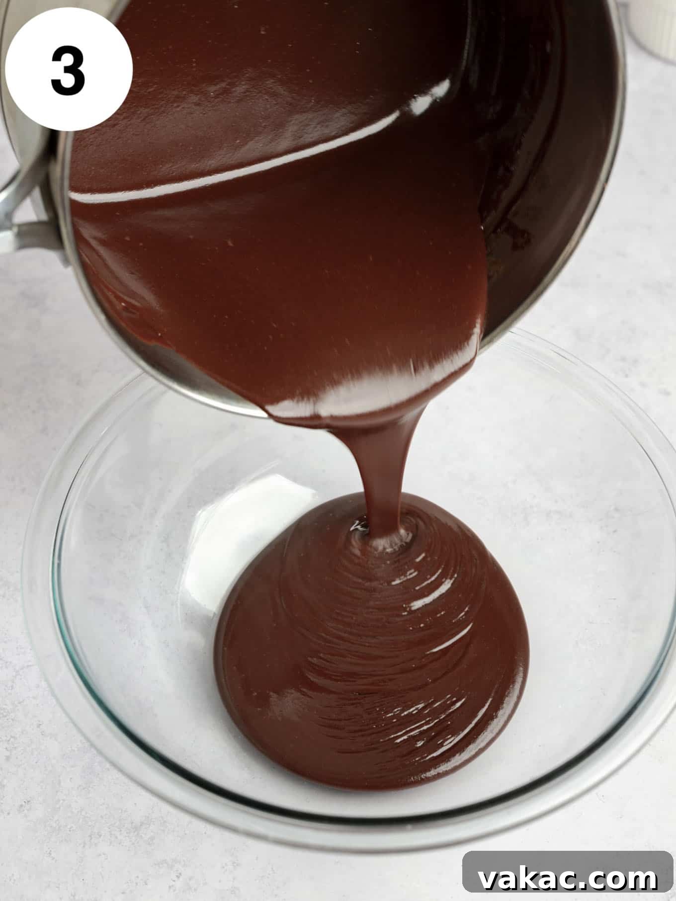 Decadent Homemade Hot Fudge Sauce 6 An action shot showing hot fudge sauce being poured into a glass bowl.