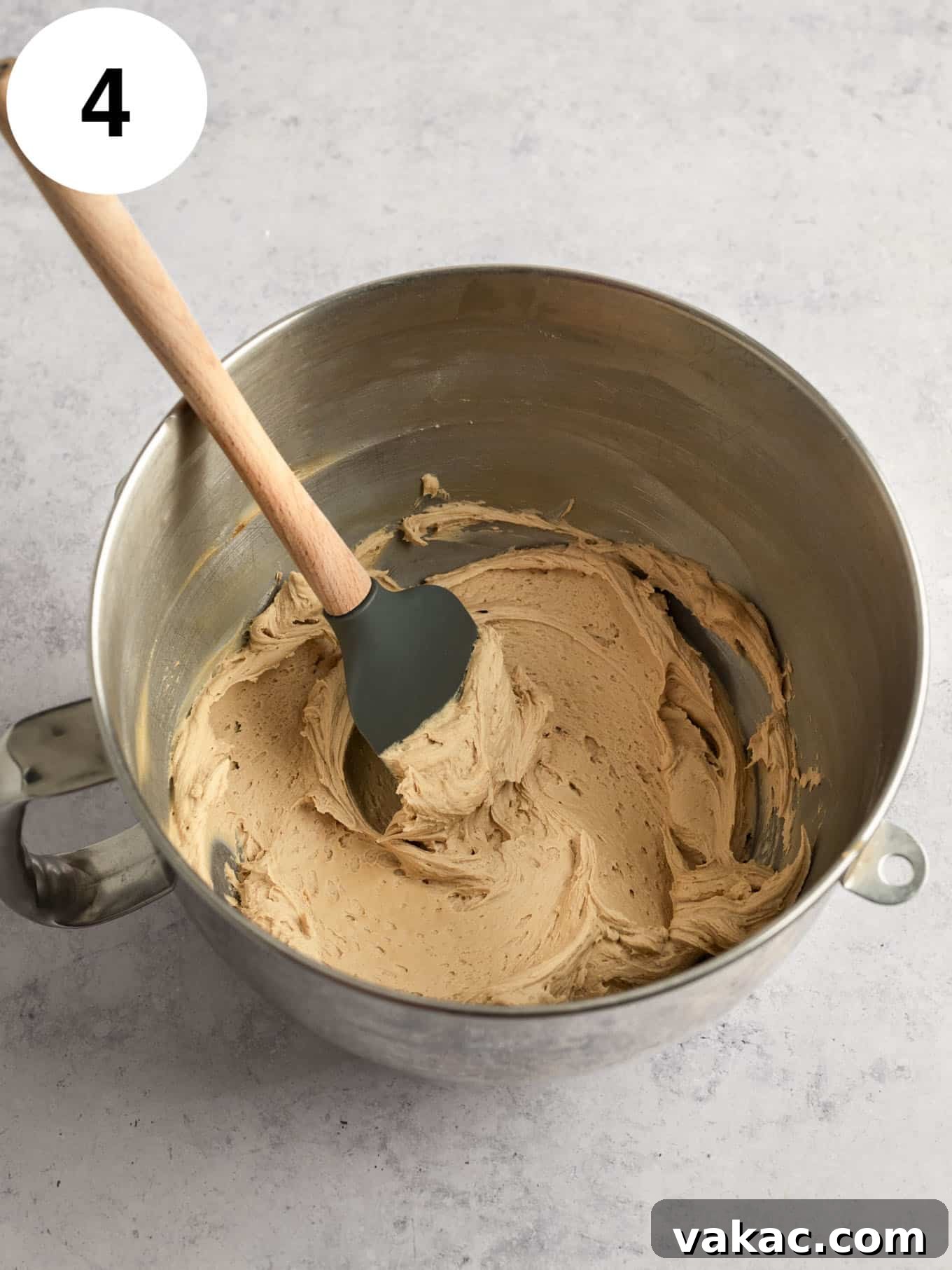 Java Dream Frost 7 Rich, creamy coffee frosting in the bowl of a stand mixer, with a rubber spatula resting nearby, highlighting its perfect, velvety texture and readiness for decorating.