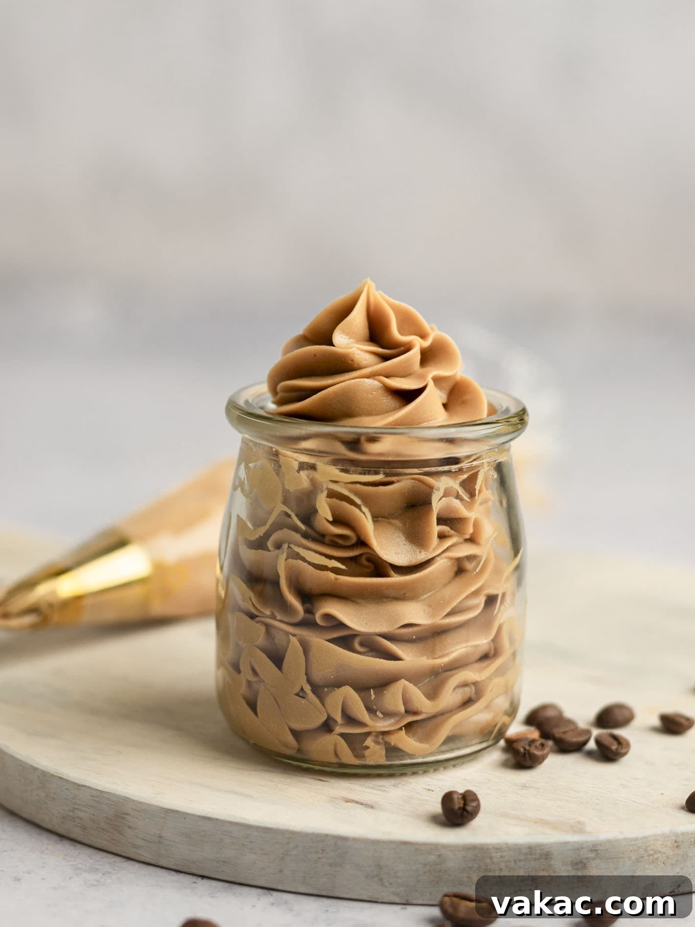 Java Dream Frost 9 Creamy coffee buttercream frosting elegantly piped into a clear glass jar, demonstrating its smooth and consistent texture and readiness for immediate use or convenient storage.
