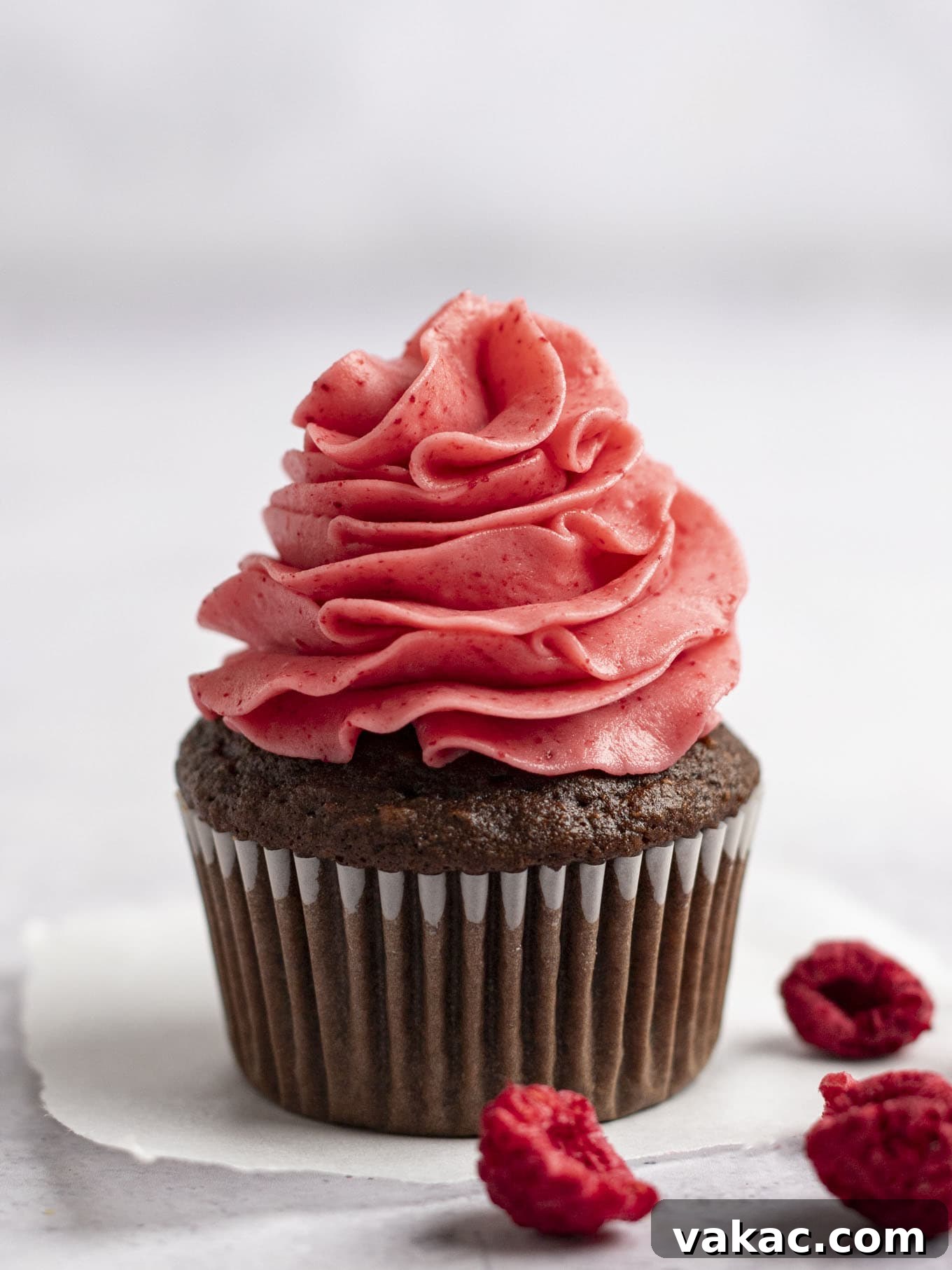 Velvet Raspberry Icing 2 A beautifully decorated chocolate cupcake topped with a generous swirl of pink raspberry frosting, showcasing its fluffy texture and vibrant color.