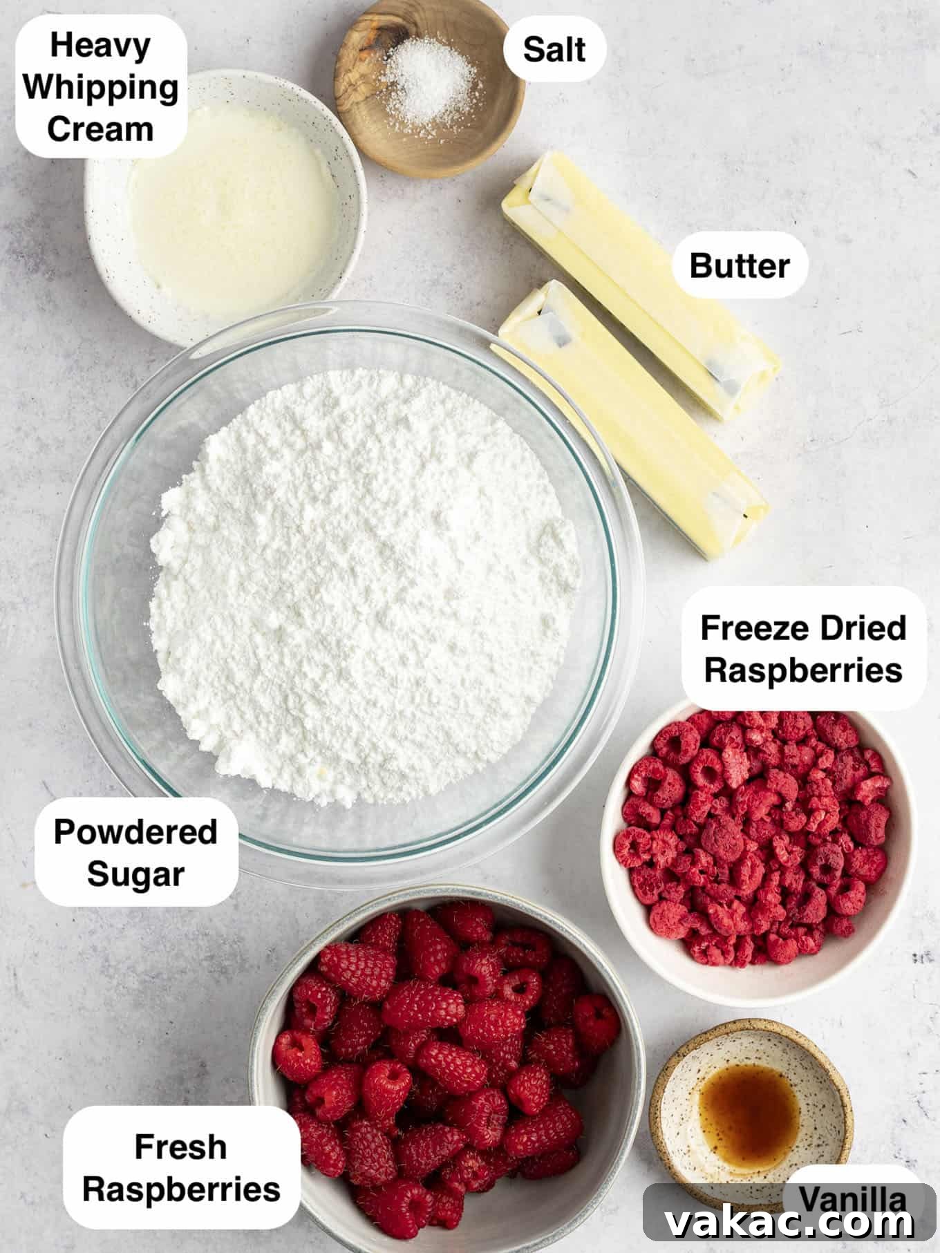 Velvet Raspberry Icing 3 An overhead flat lay photo of the essential ingredients laid out for making raspberry buttercream frosting, including fresh raspberries, butter, powdered sugar, and vanilla extract.