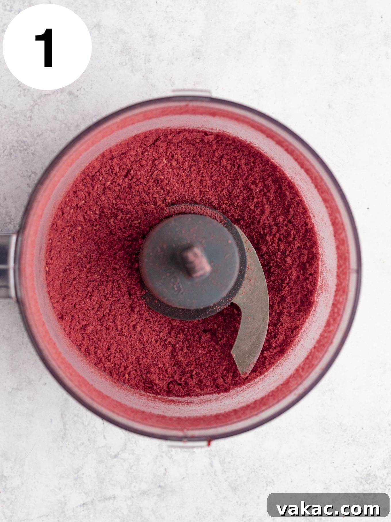Velvet Raspberry Icing 4 An overhead view of finely ground freeze-dried raspberry powder in the bowl of a food processor, ready for sifting.