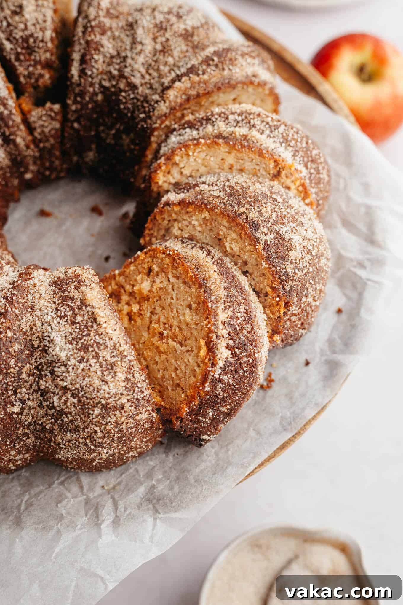 Cinnamon Sugar Cider Cake 2 A sliced apple cider donut bundt cake on parchment paper.