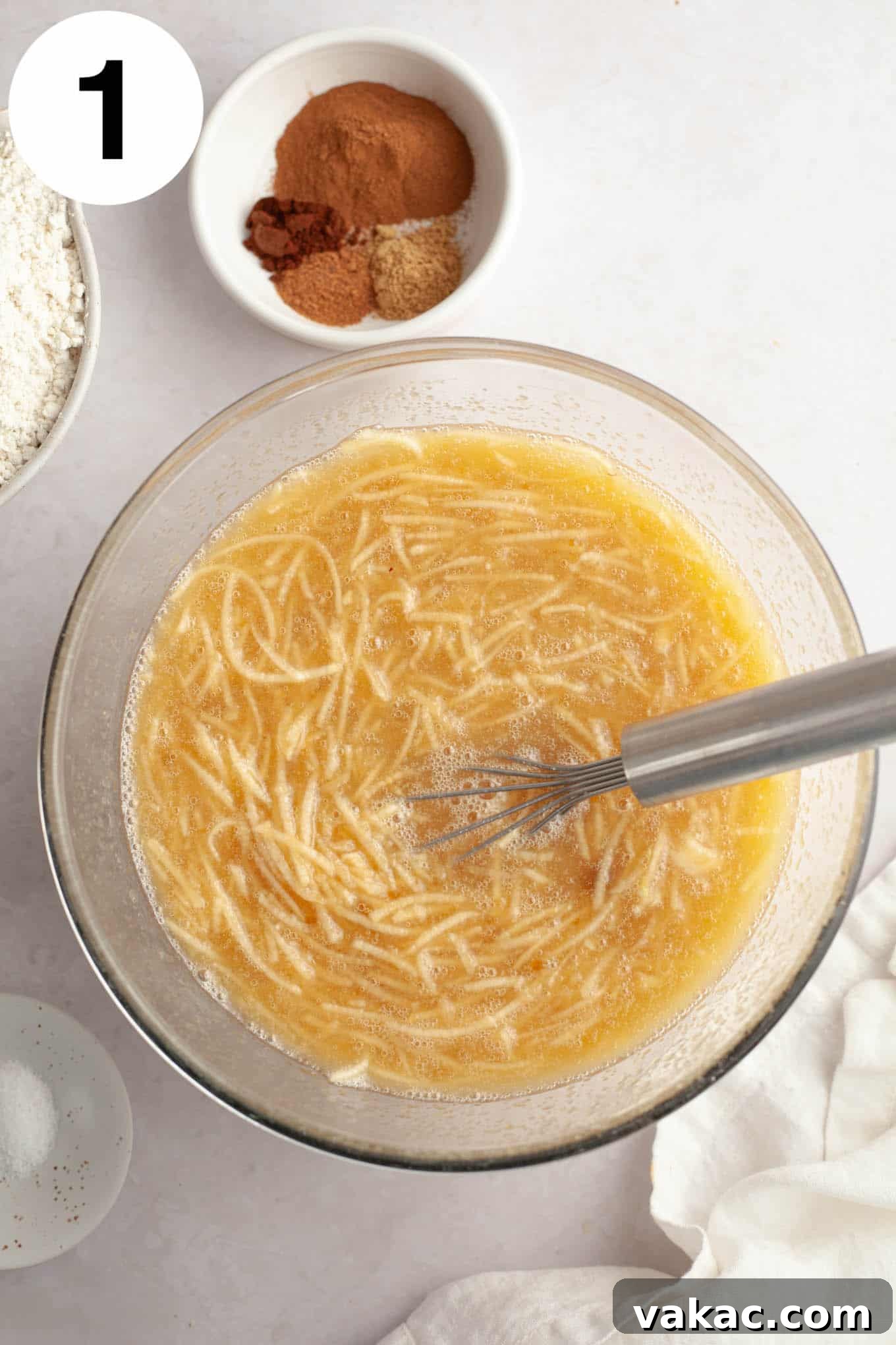 Cinnamon Sugar Cider Cake 4 An overhead view of the wet ingredients with grated apple, in a glass mixing bowl with a whisk.