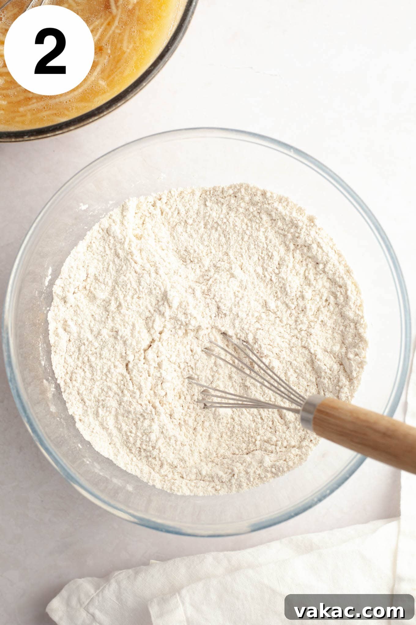 Cinnamon Sugar Cider Cake 5 An overhead view of a flour and spice mixture, in a glass mixing bowl with a whisk.