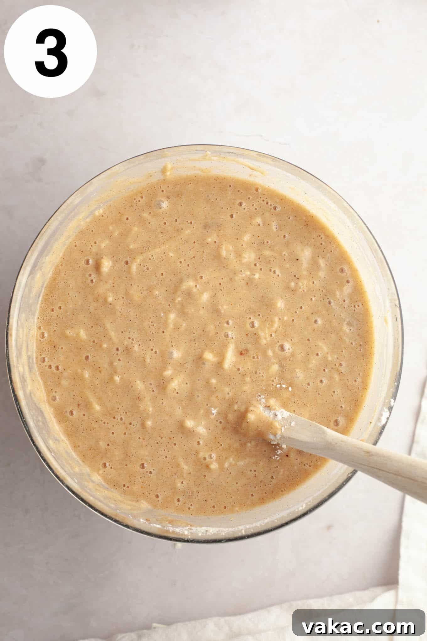 Cinnamon Sugar Cider Cake 6 An overhead view of apple cake batter, in a glass mixing bowl with a wooden spoon.